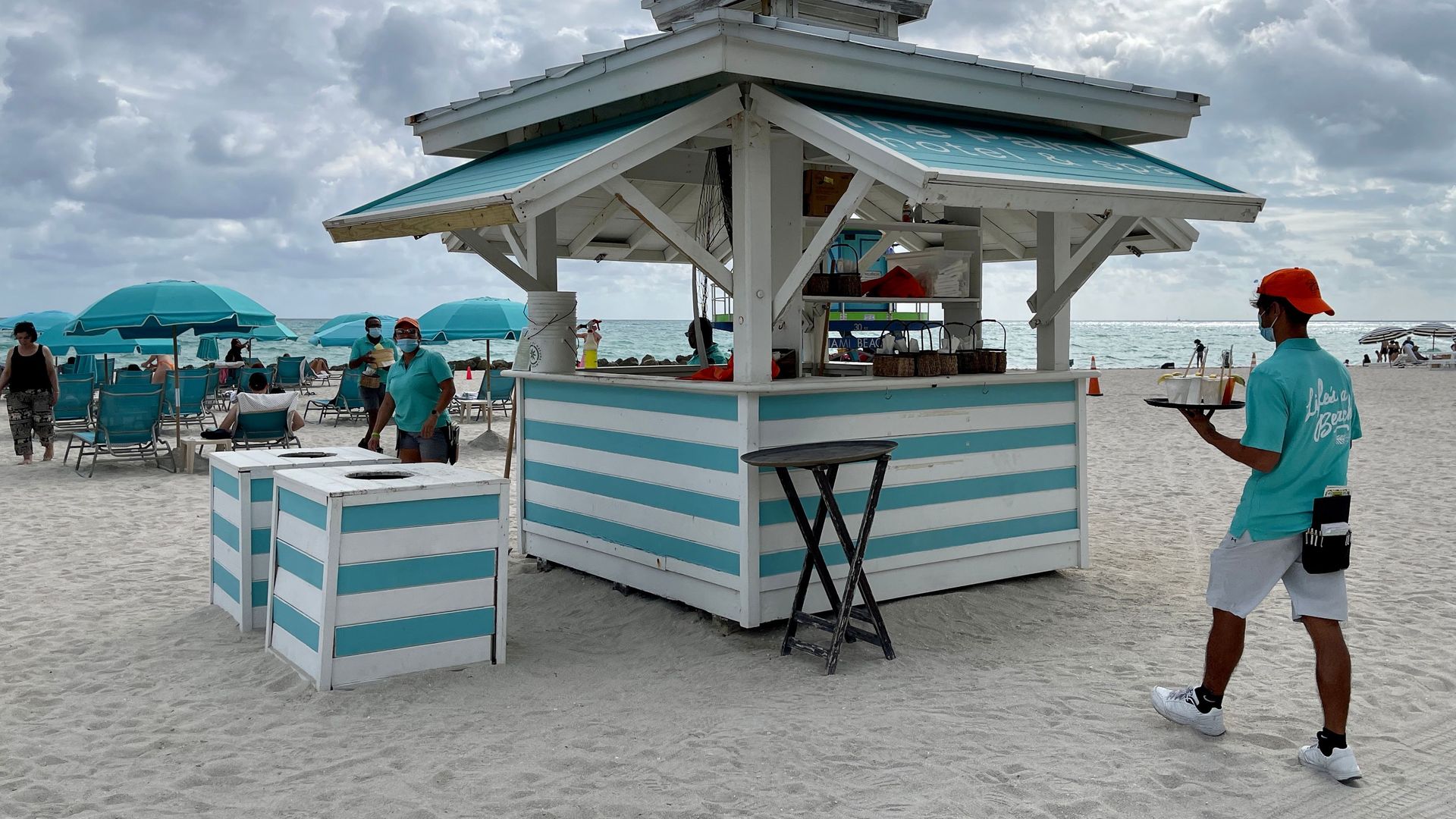 A waiter carries cocktails from a beach bar in Miami, Florida, on December 20, 2020, amid the Coronavirus pandemic. (Photo by Daniel SLIM / AFP) (Photo by DANIEL SLIM/AFP via Getty Images)
