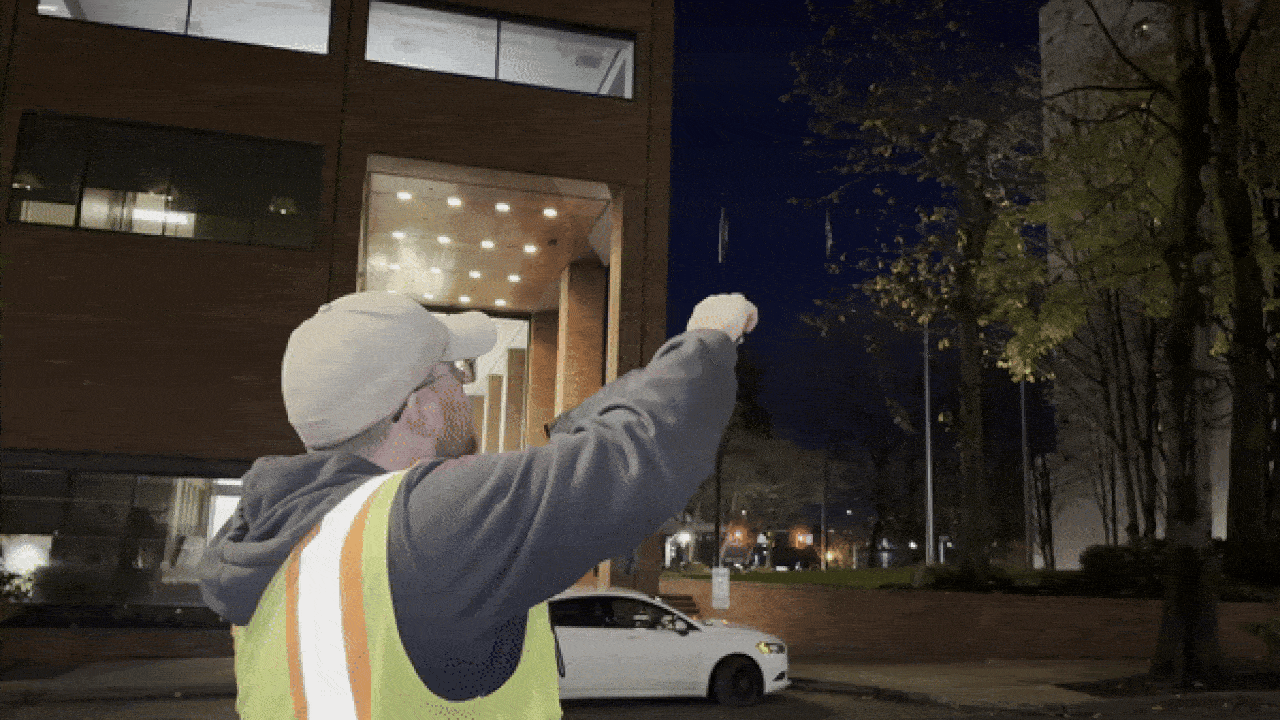 An animated gif shows a man in a yellow vest calling to a hawk that flies to him and lands on his gloved arm.