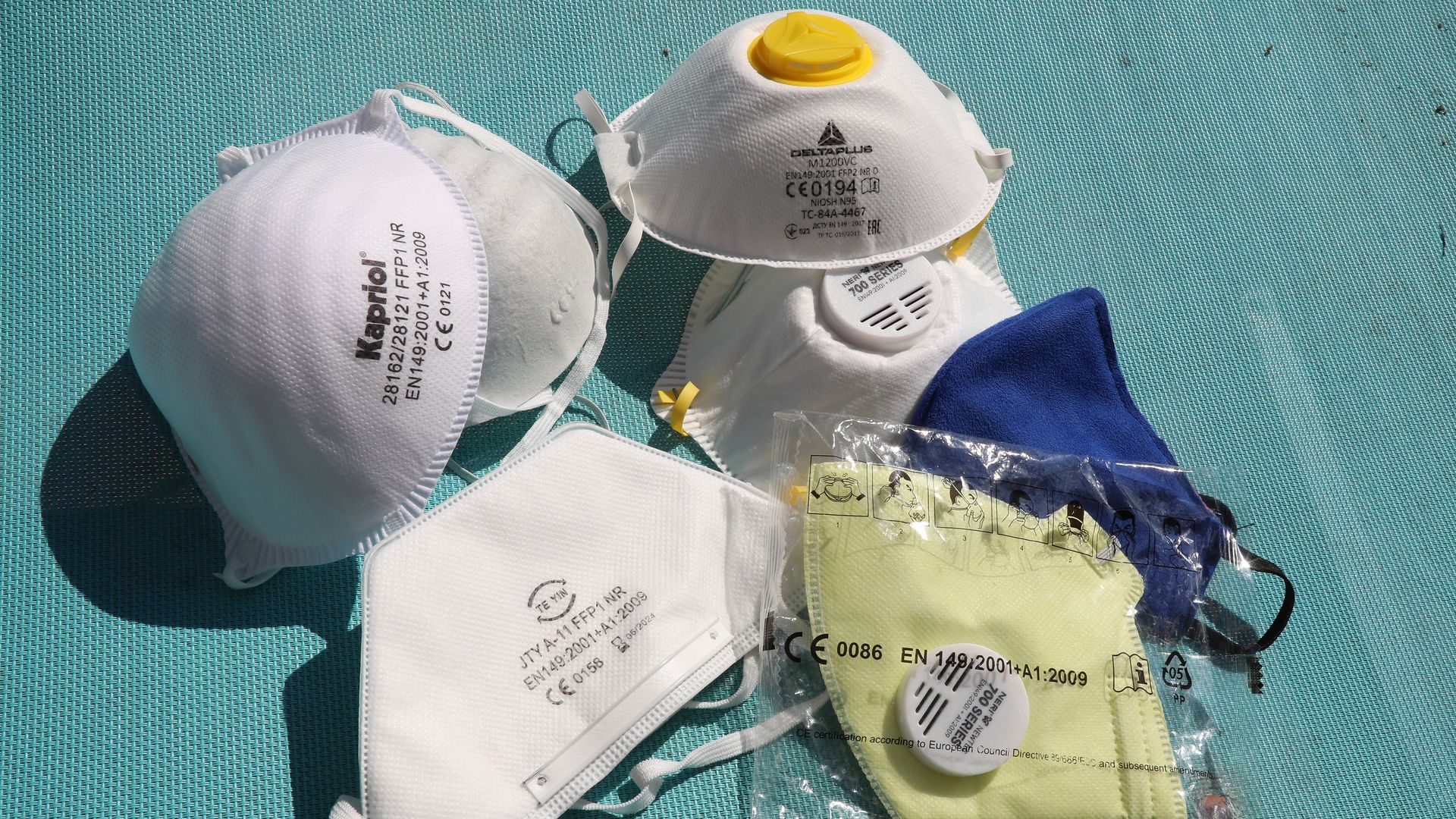 In this image, a pile of N95 masks and surgical masks are on a table