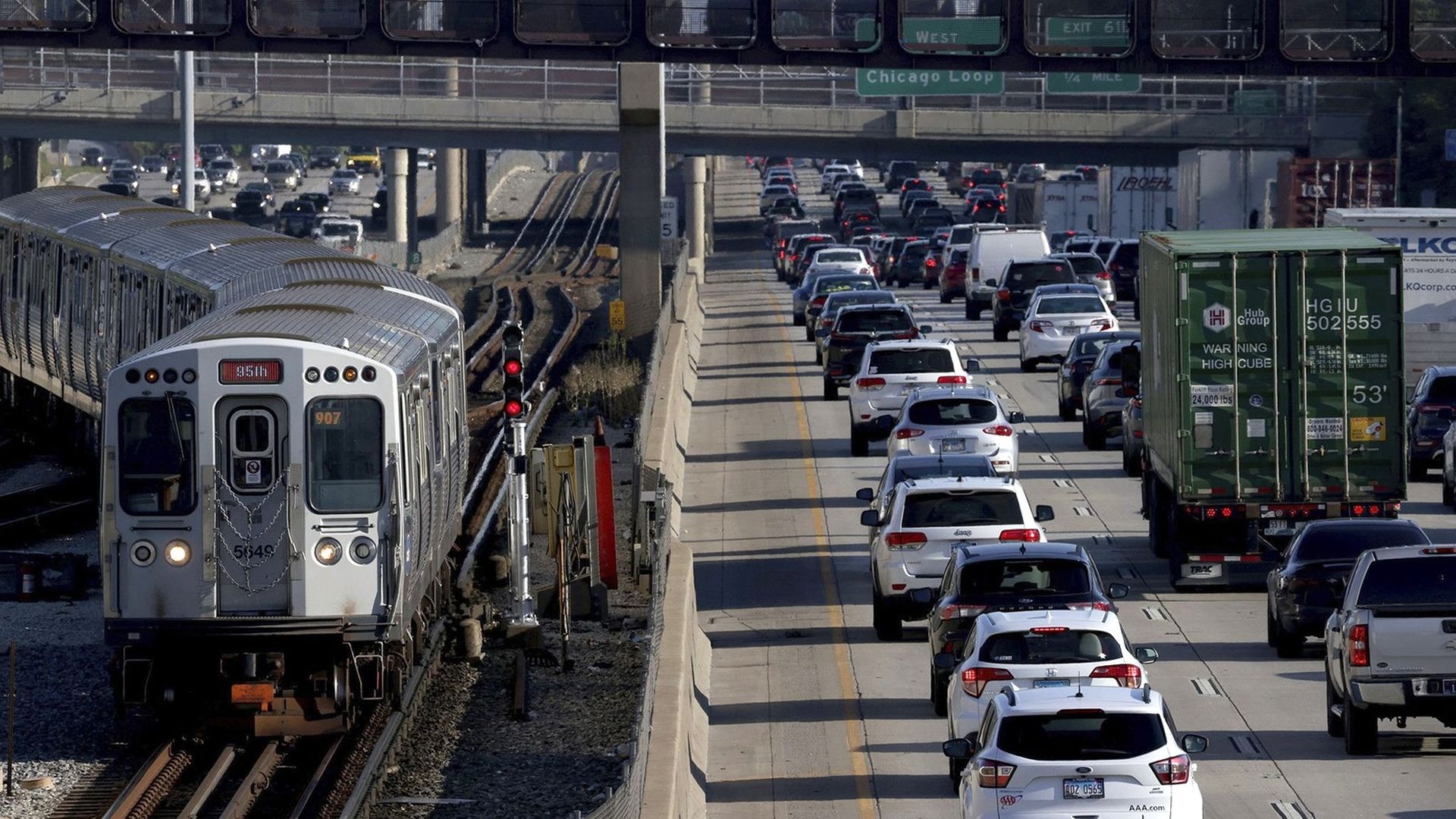 Photo of a train on tracks that are next to highway traffic 