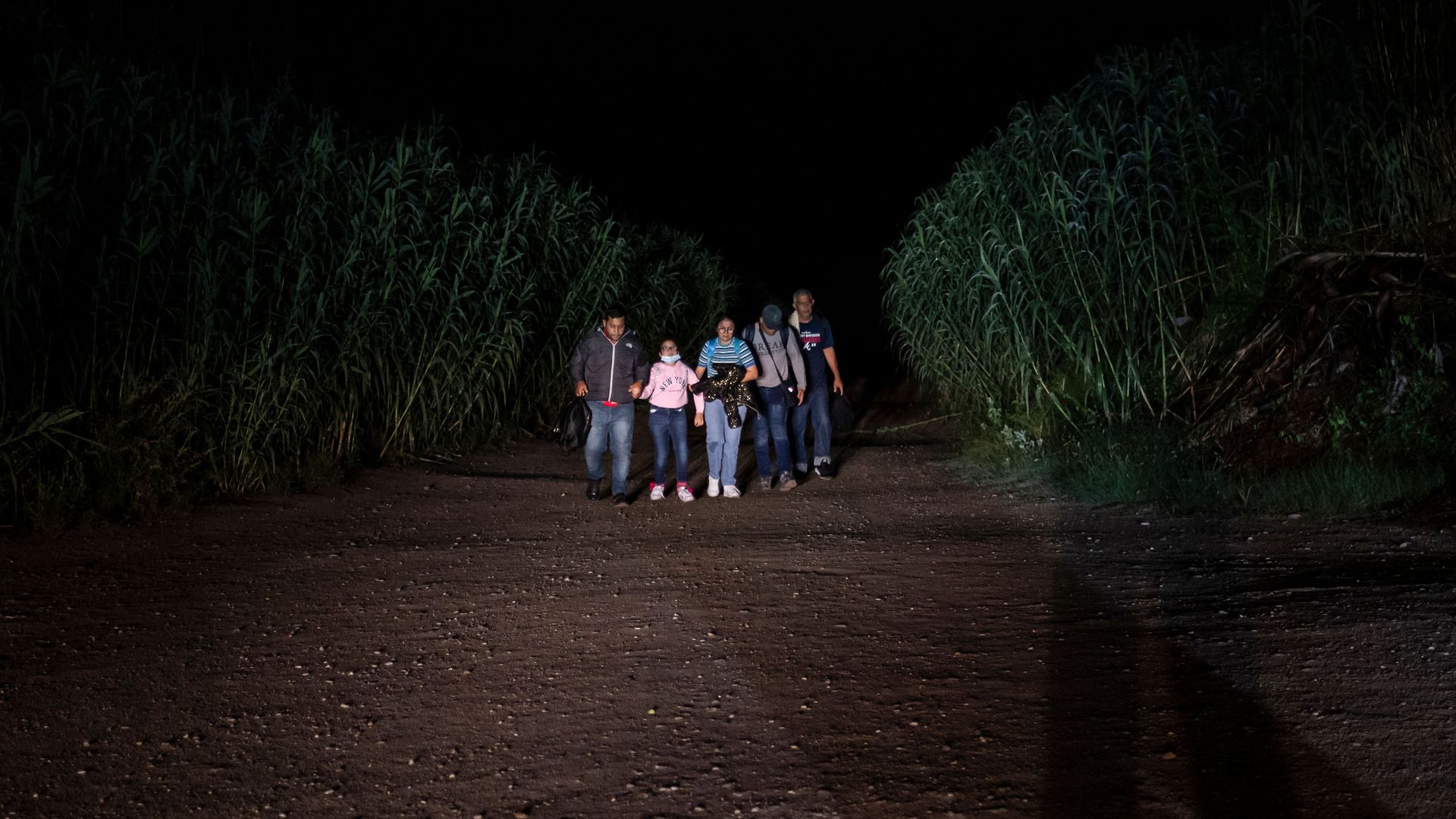 Picture taken at night of a family in the middle of a field after having crossed the Rio Grande