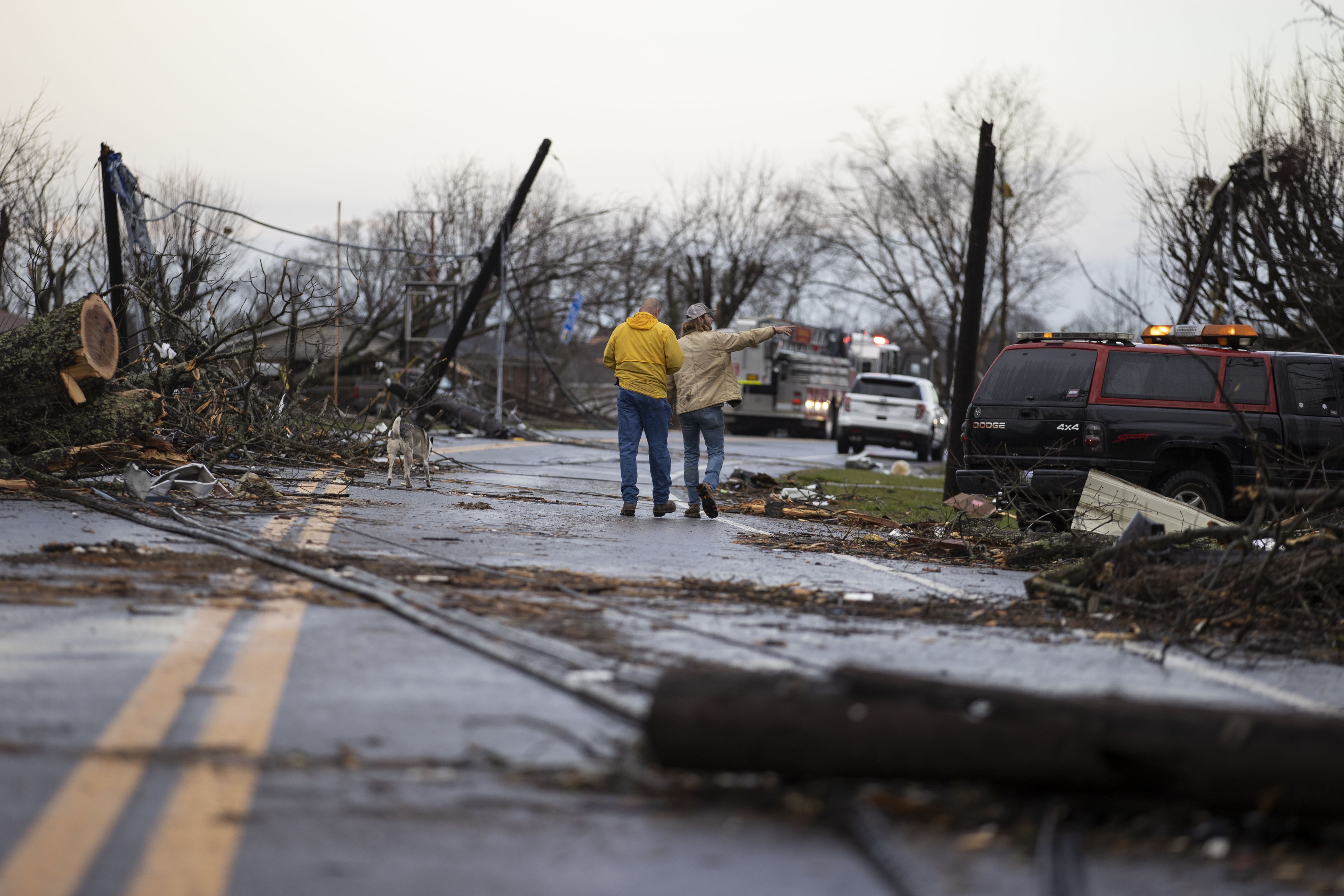 Residents walk through downed utility lines and trees to survey damage