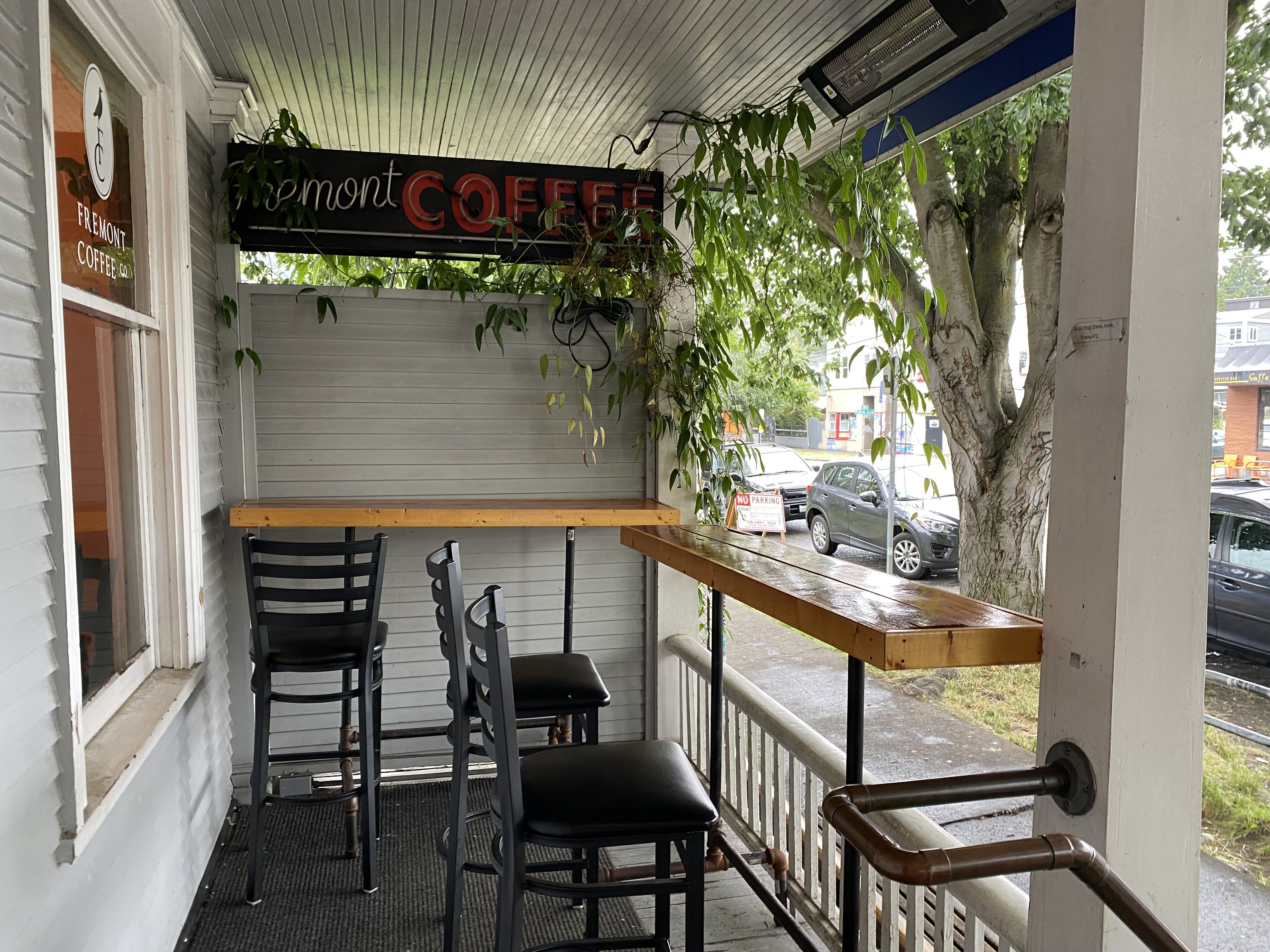 Barstool seating at a wooden counter facing a sidewalk, with a sign that says "Fremont Coffee Co" above.
