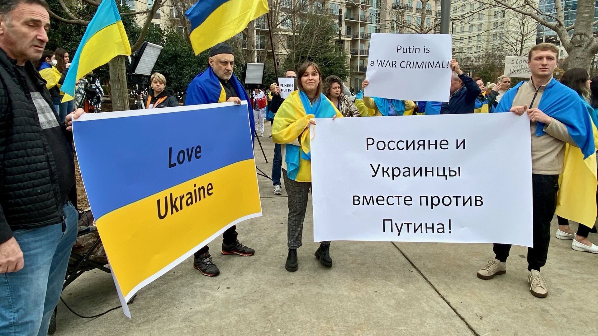 Dozens of protestors holding blue and yellow flags gather at Romare Beareden park. They're holding signs that read "love Ukraine" and "Putin is a war criminal."