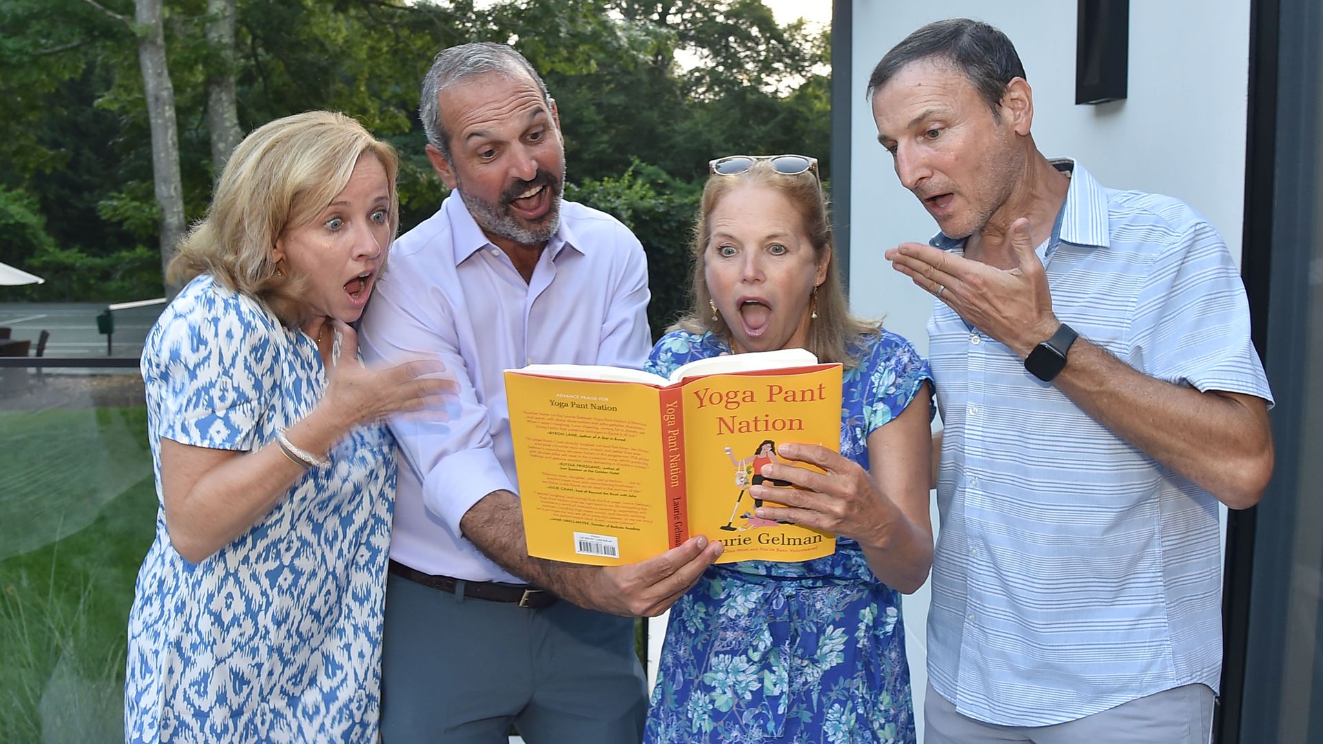 Katie Couric holds a book with a shocked expression on her face.