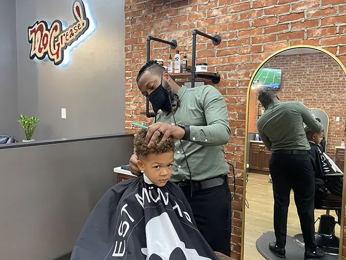 Young child receives haircut at No Grease!