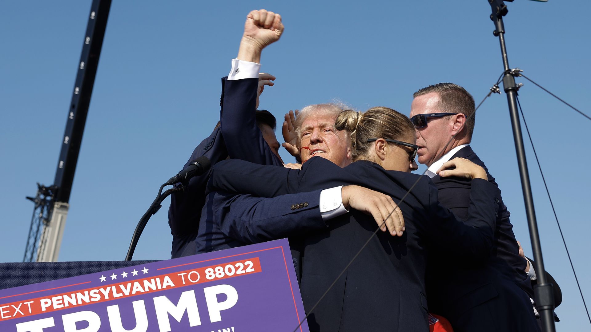 : Republican presidential candidate former President Donald Trump pumps his fist as he is rushed offstage during a rally on July 13, 2024 in Butler, Pennsylvania. Butler County district attorney Richard Goldinger said the shooter is dead after injuring former U.S. President Donald Trump, killing one