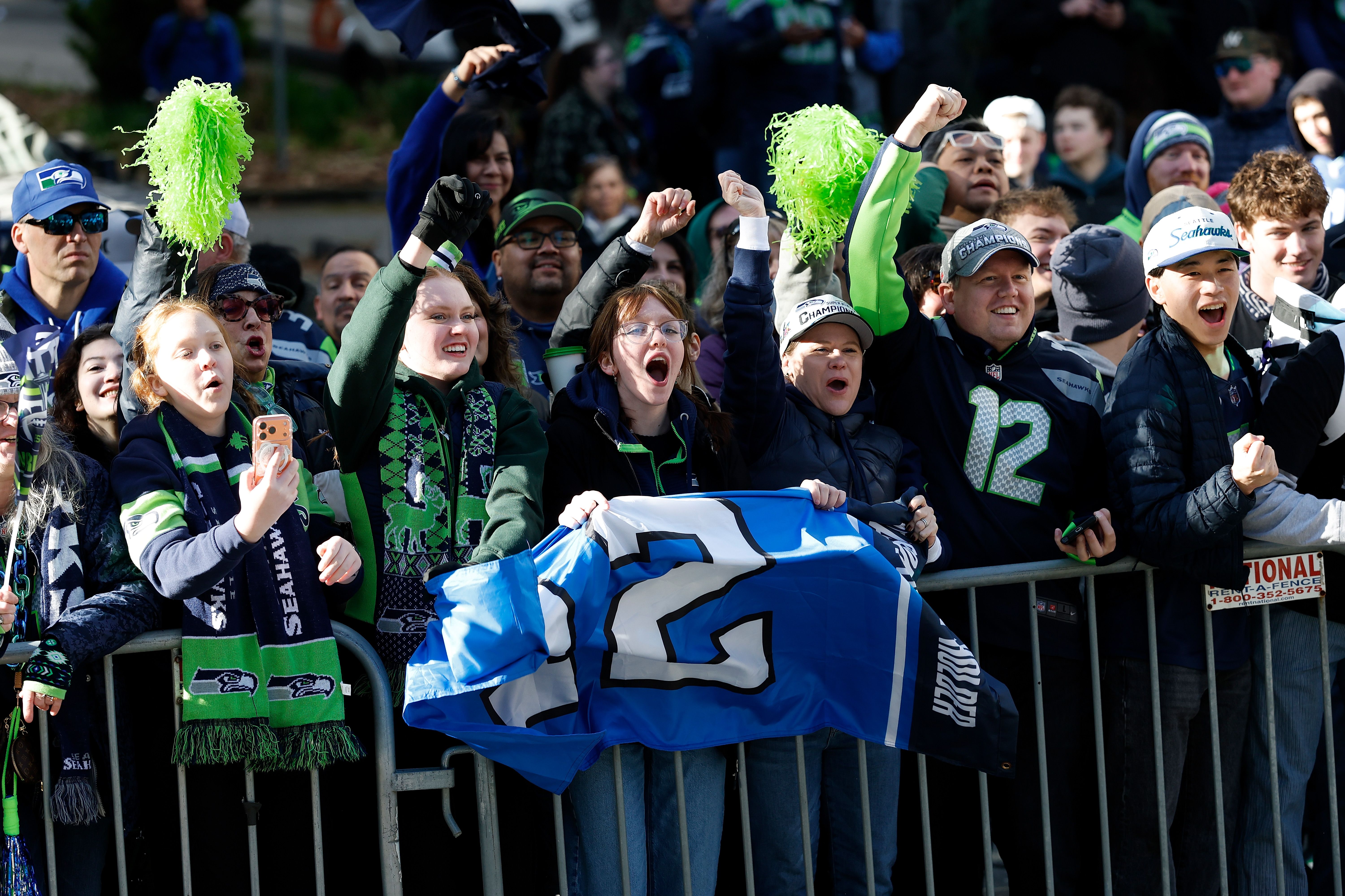 Seattle Seahawks fans in blue and green line the route.