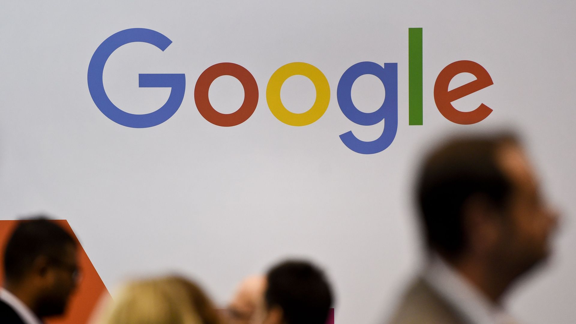 People walk past a Google logo on a wall in Lisbon