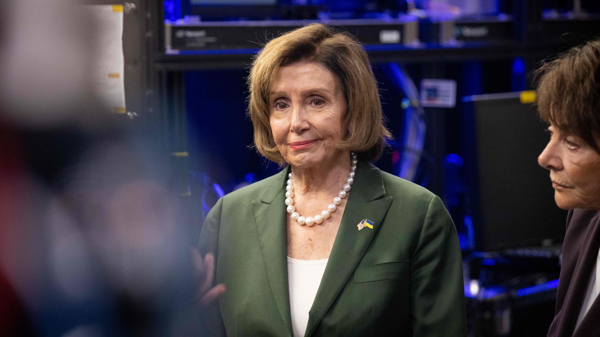 House Speaker Nancy Pelosi, wearing a green suit, white shirt and pearl necklace, at the National Accelerator Laboratory in California.