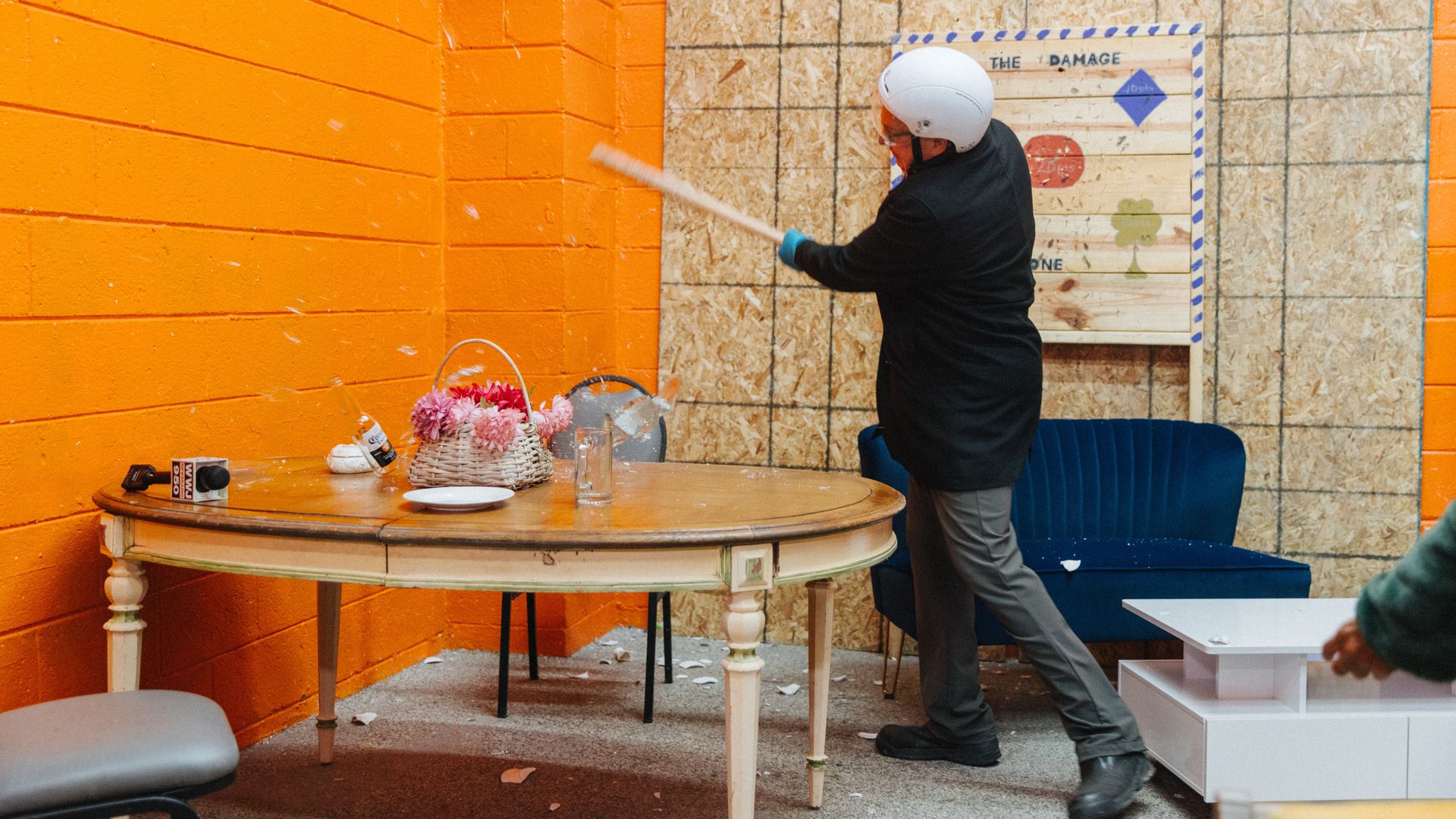 A person with a helmet smashes an item with a bat.