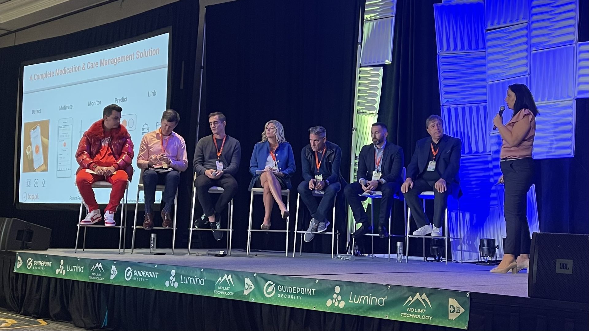 Investors on a stage listening to a presentation from Tamir Sapir