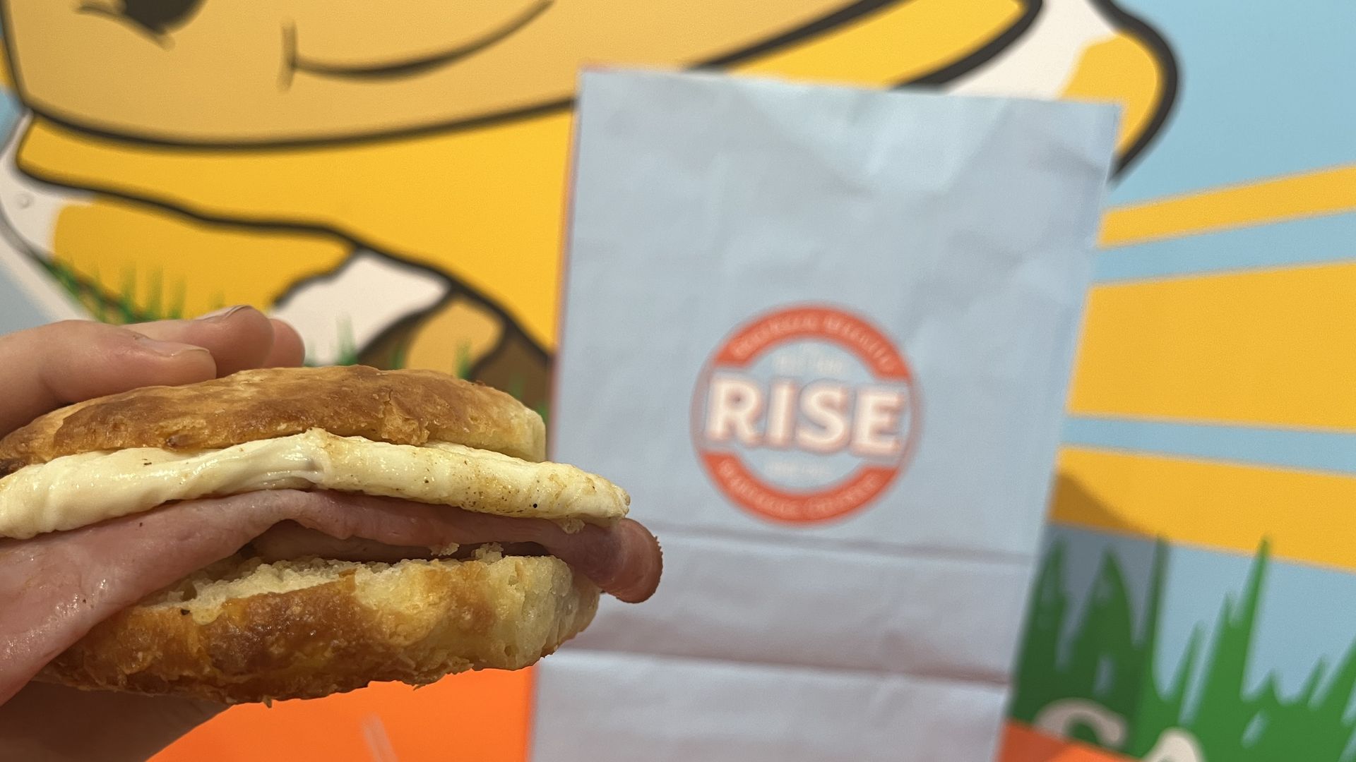 A hand holding up a ham, egg and cheese biscuit 