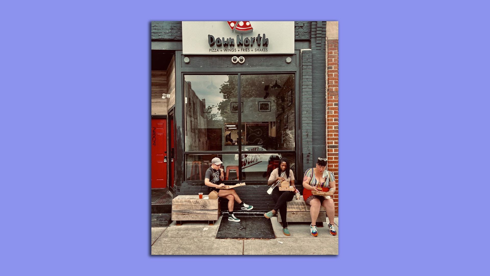 Three people eat outside Down North pizzeria in Philly's Strawberry Mansion neighborhood.