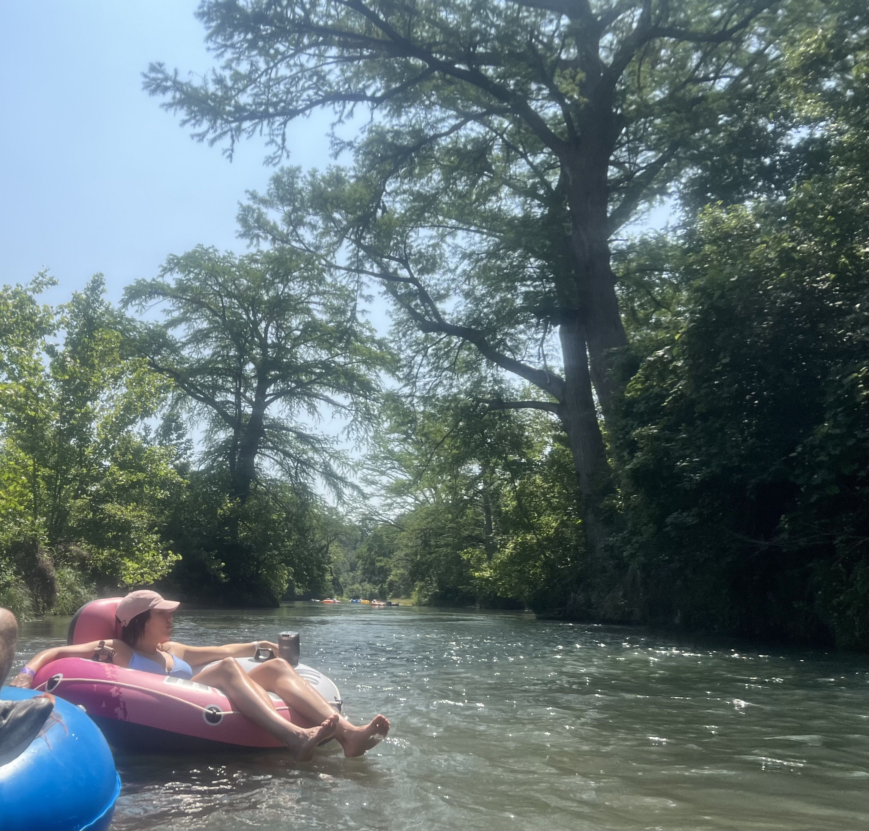 A woman sits on a tube while floating down the tree-lined San Marcos River.