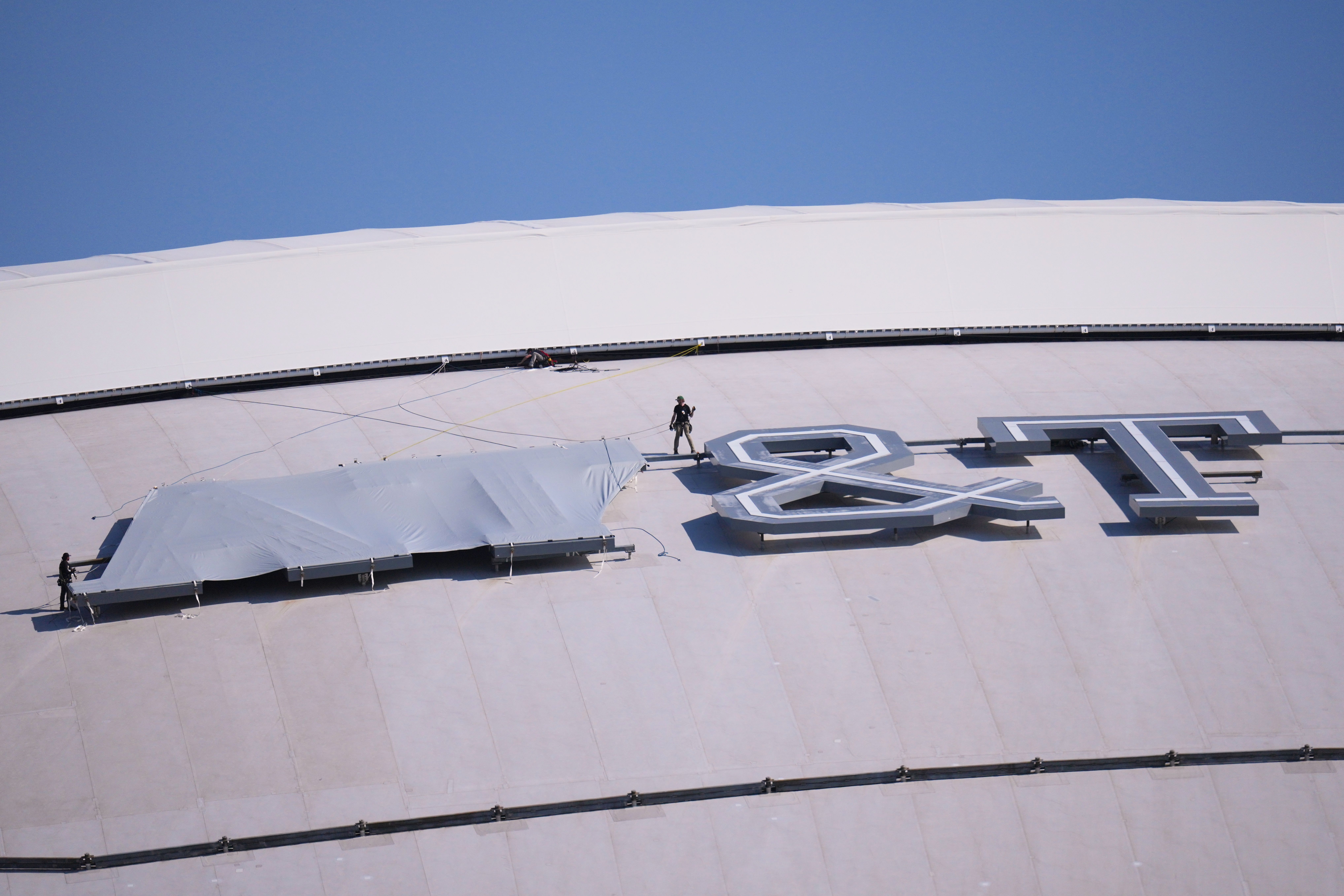 Workers block the AT&T logo at AT&T Stadium yesterday in Arlington, Texas. AP Photo/Julio Cortez