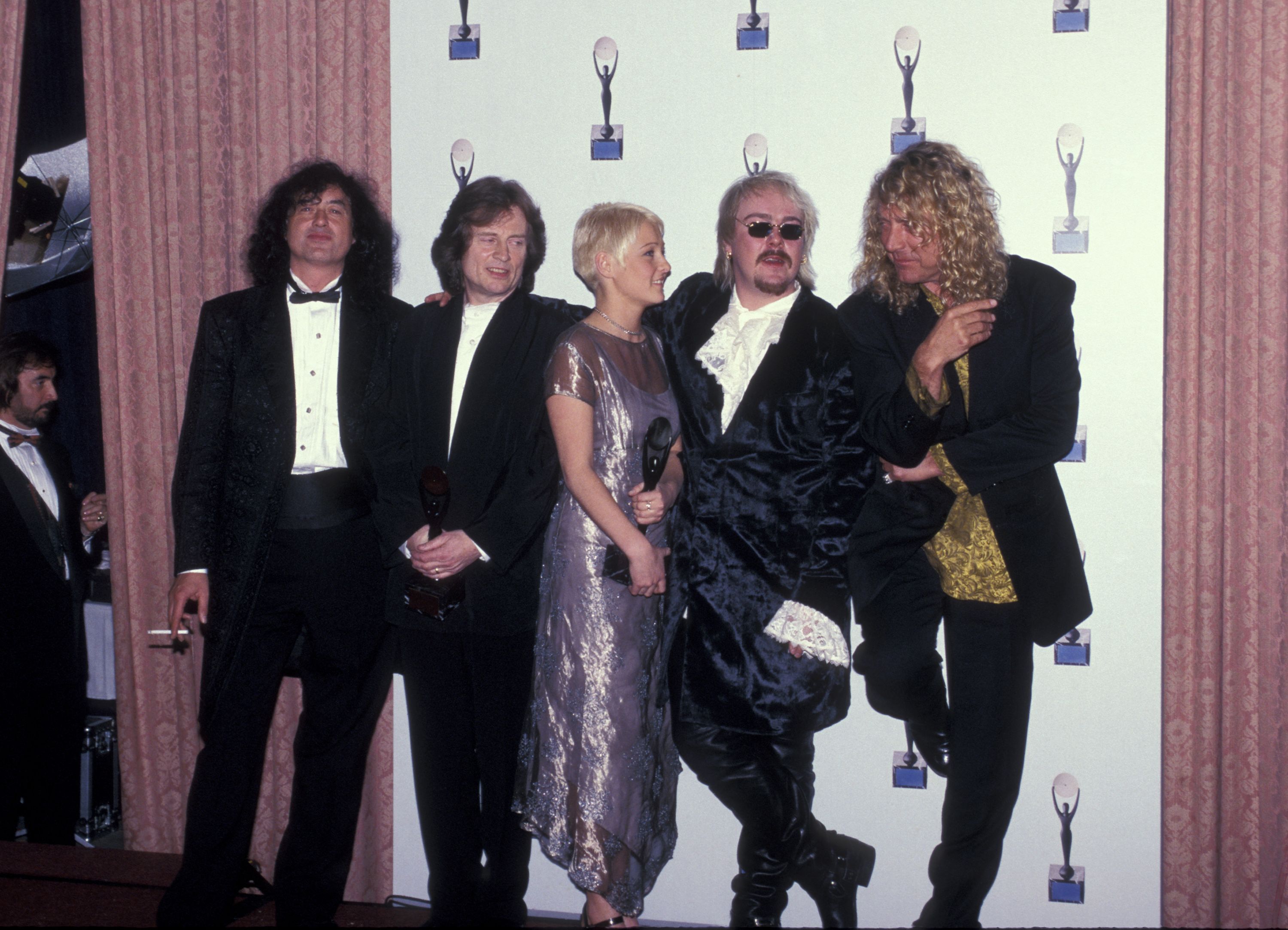 The members of Led Zeppelin pose for a photo on a red carpet. 