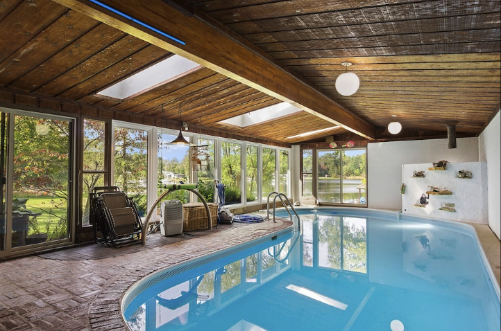 A lake is seen through windows looking out from an indoor pool.