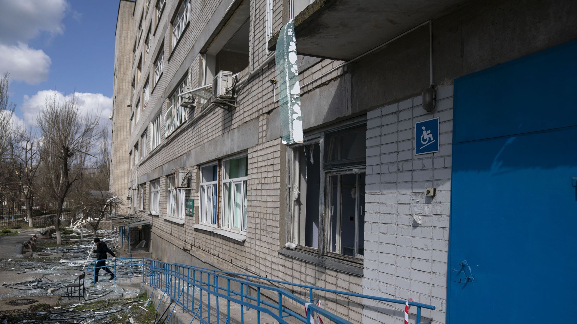 Picture of a person standing in front of a destroyed Ukrainian hospital