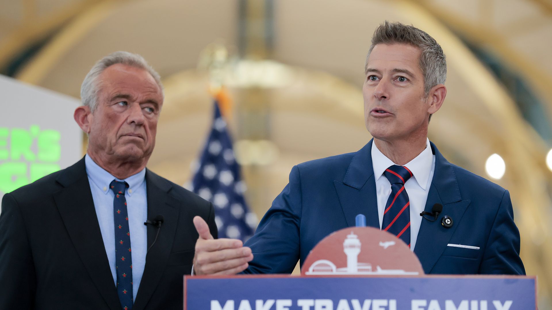 RFK Jr. wearing a dark blue suit jacket, light blue shirt and blue tie with red designs and Duffy wearing a light blue suit jacket, white shirt and red and blue striped tie