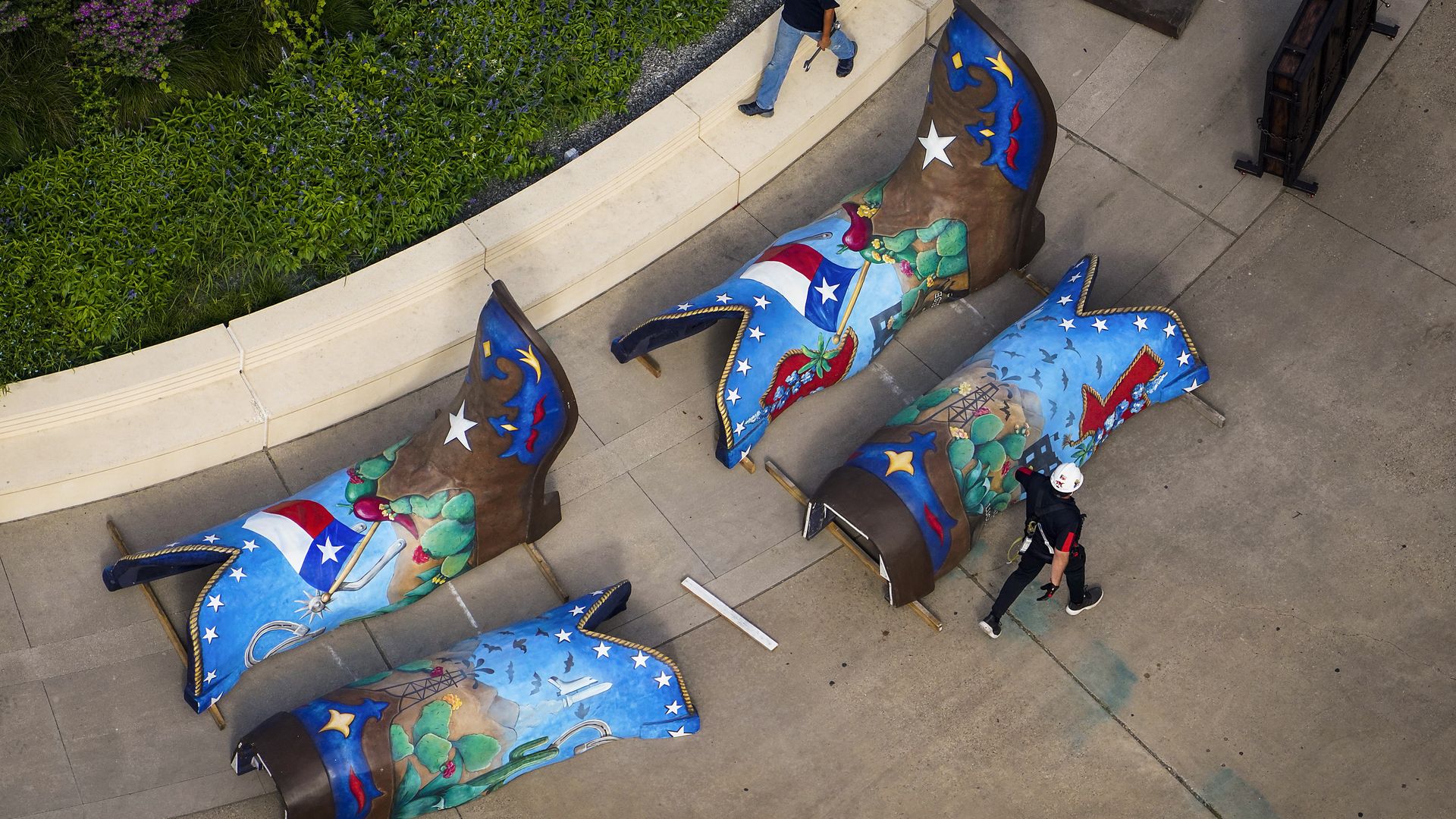 Two pairs of 12-foot boots lay on pavement