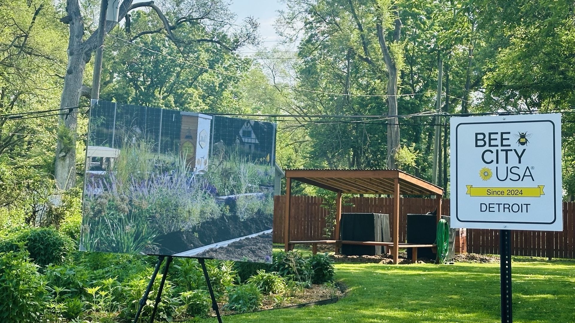 A "Bee City USA" sign next to a native plants garden, and a poster showing future planned improvements.