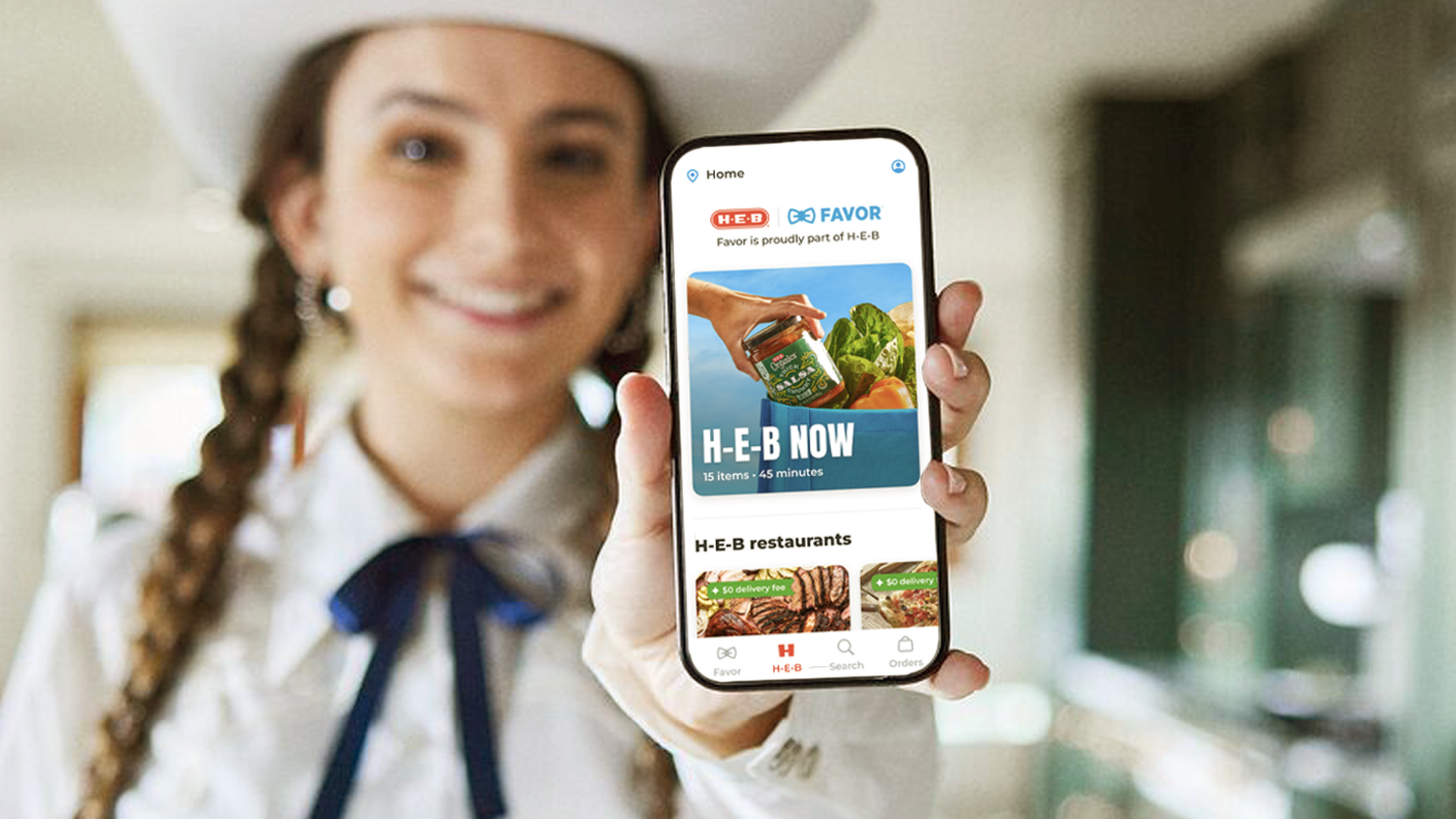 A woman wearing a white cowboy hat holds a phone to the camera. 