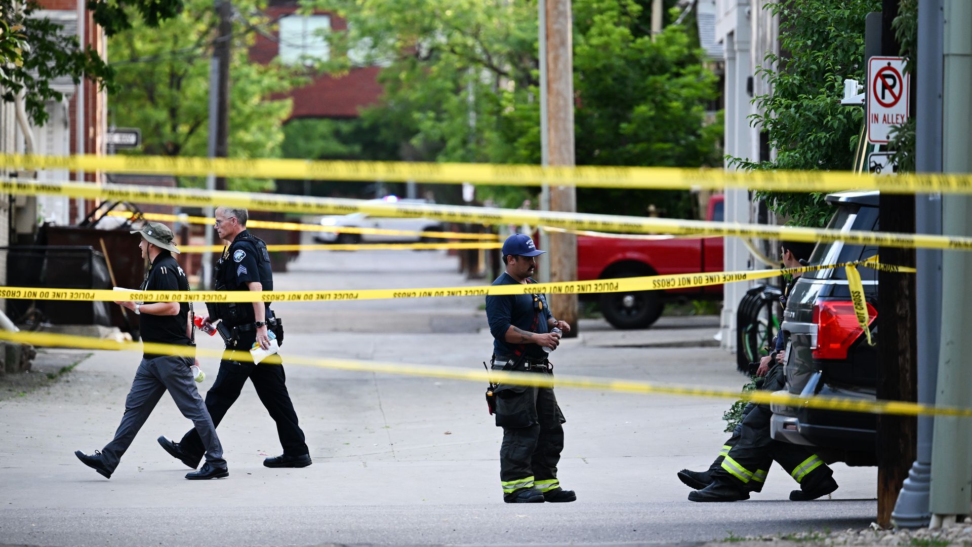 Police officers walk behind yellow crime scene tape during an attack on Boulder's Pearl Street Mall.