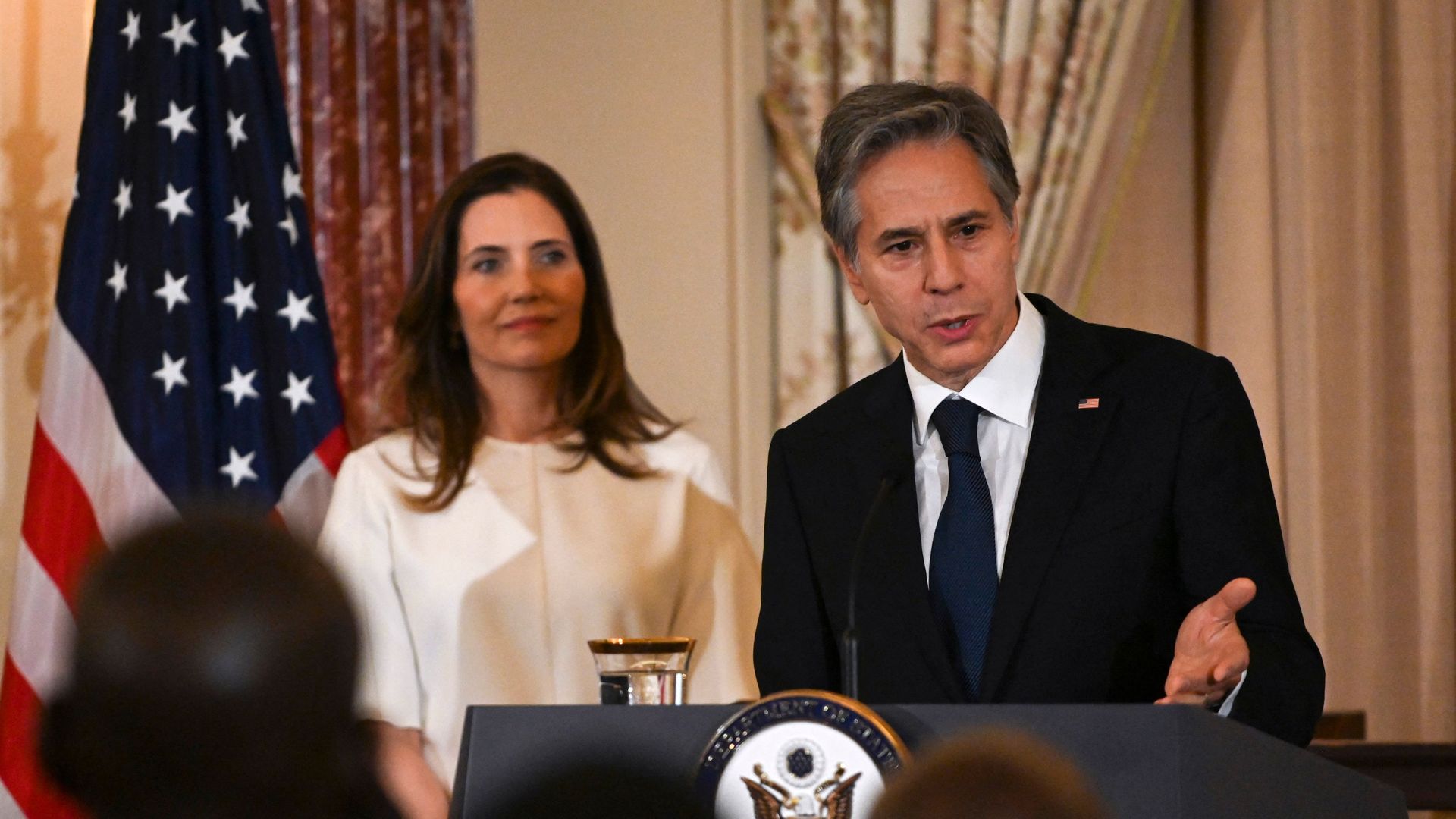 Photo of Antony Blinken speaking from a podium while Evan Ryan stands behind him