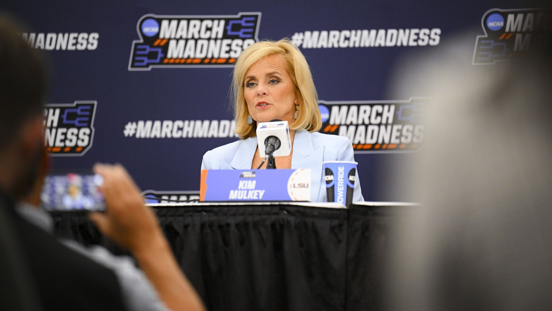 Kim Mulkey speaks into a microphone during a press conference.