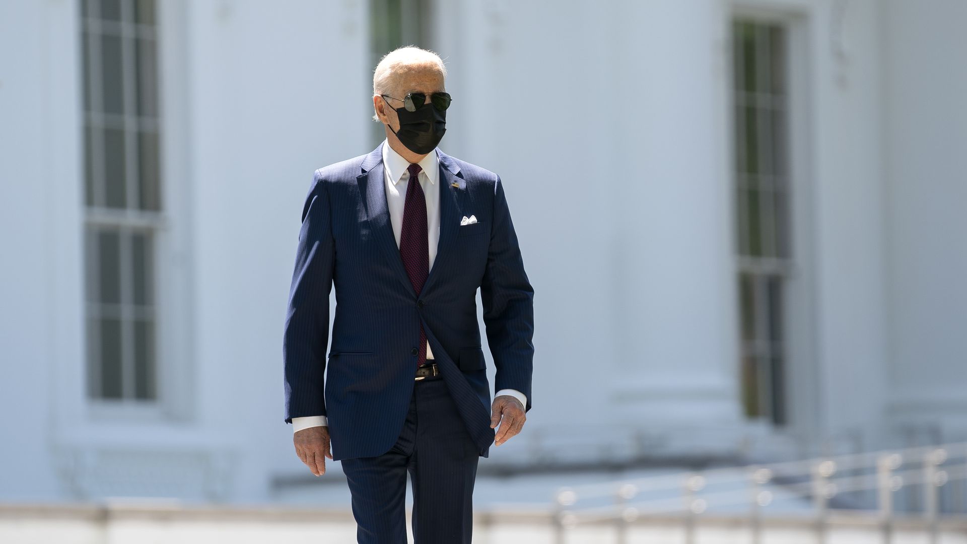 Photo of Joe Biden in a mask and sunglasses walking 