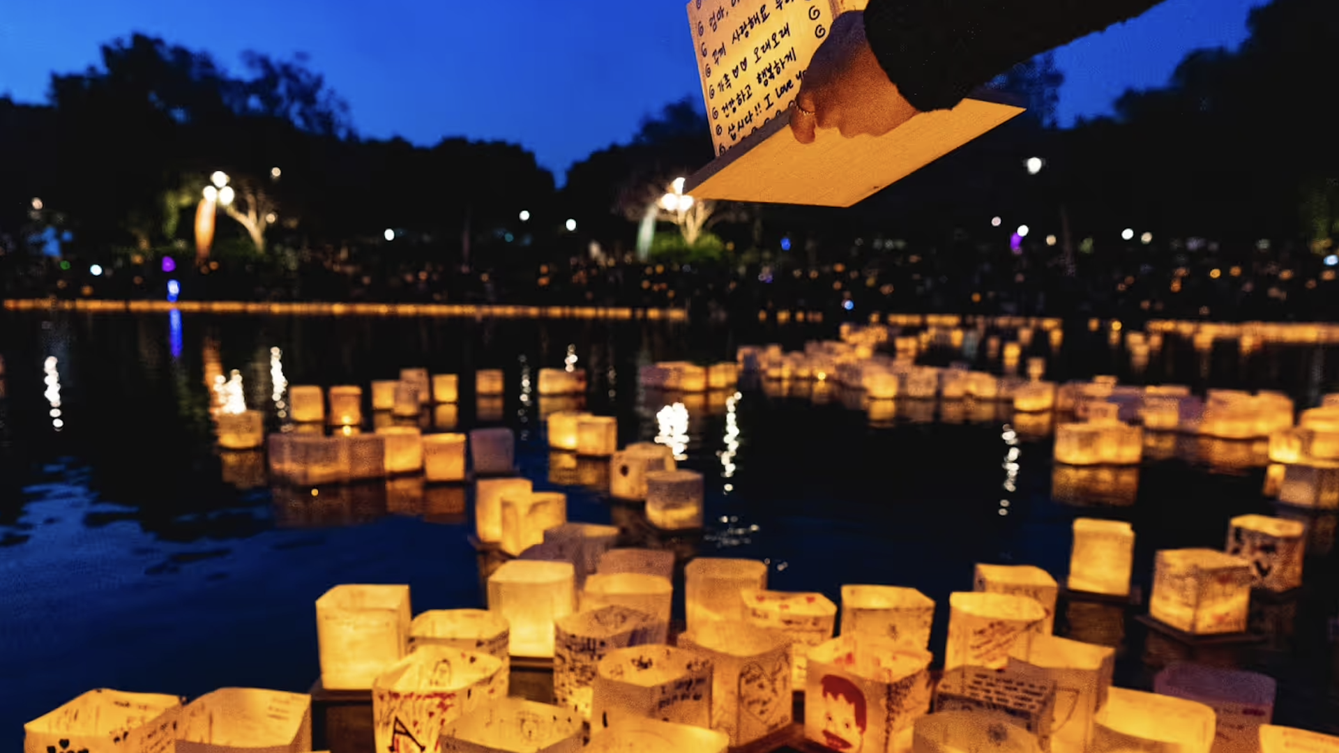 Paper lanterns sit lit up on a waterway