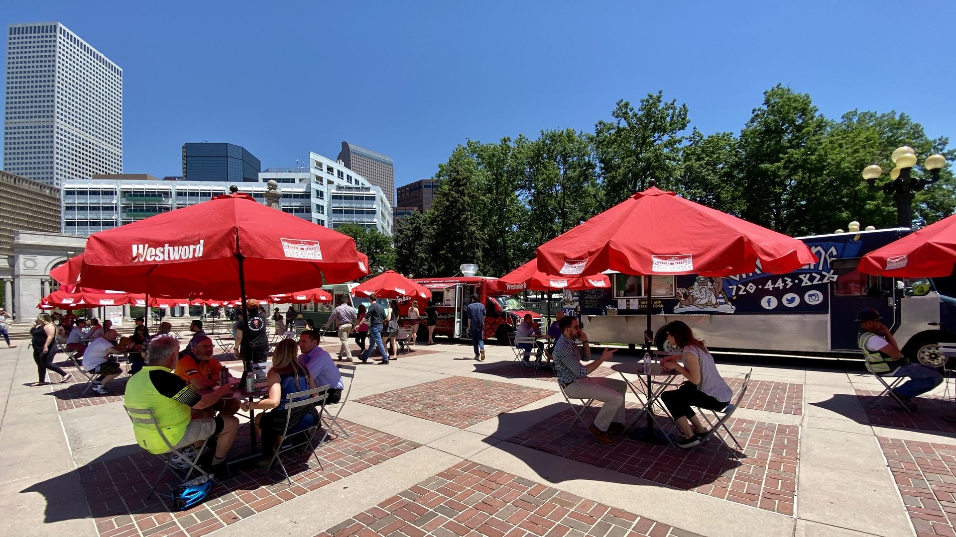 A photo of a food truck court with people seated and eating at tables