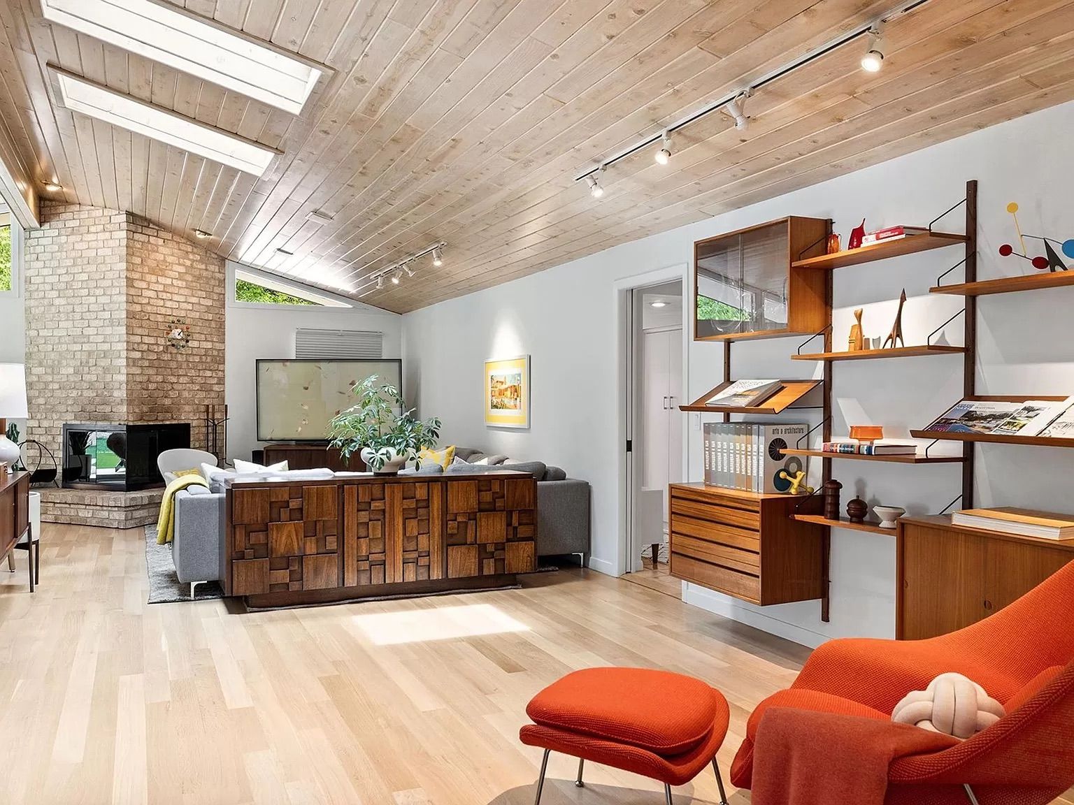 A living room with vaulted ceilings, dark shelves, gray walls and gray furniture.