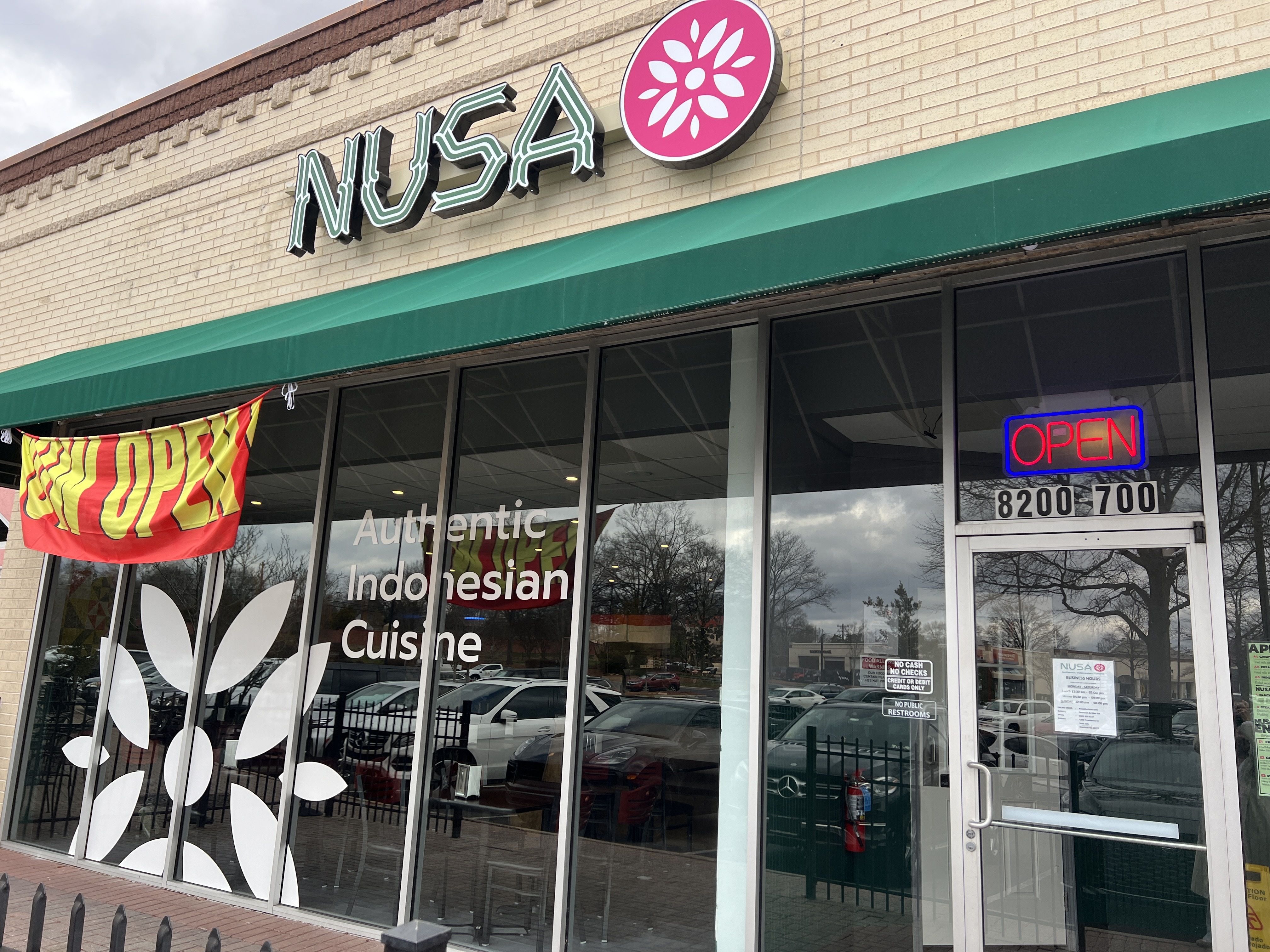Outside of restaurant with signage that reads "Nusa" and "now open"