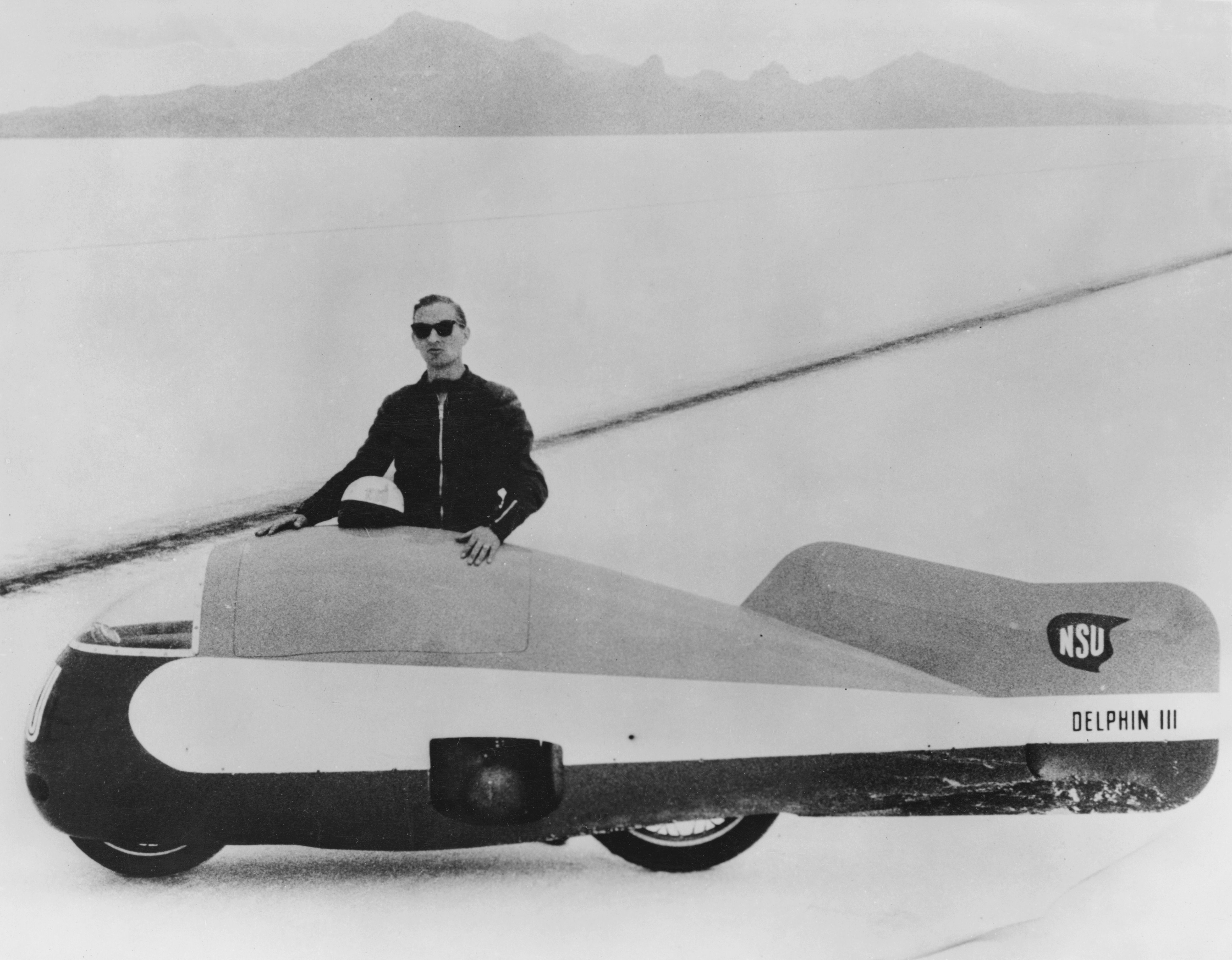 German land speed racer Wilhelm Herz (1912 - 1998) with his 500cc NSU Delphin III motorcycle at the Bonneville Salt Flats in Utah, USA, where he established a new world motorcycle speed record, 8th August 1956. The vehicle is fitted with a streamlined shell.