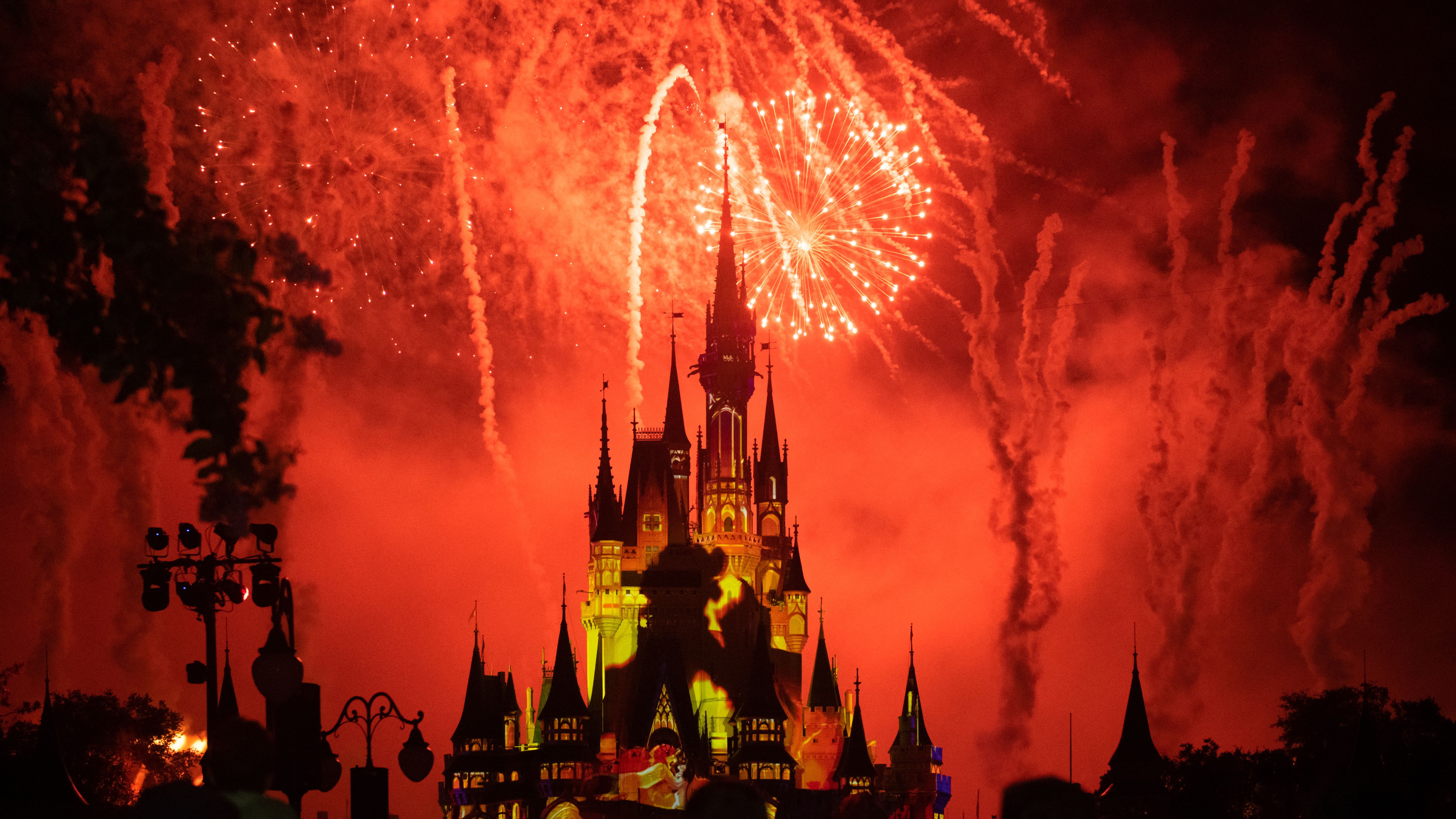 Red fireworks and yellow strobe lights illuminating the Cinderella Castle in the Walt Disney's Magic Kingdom theme park. 