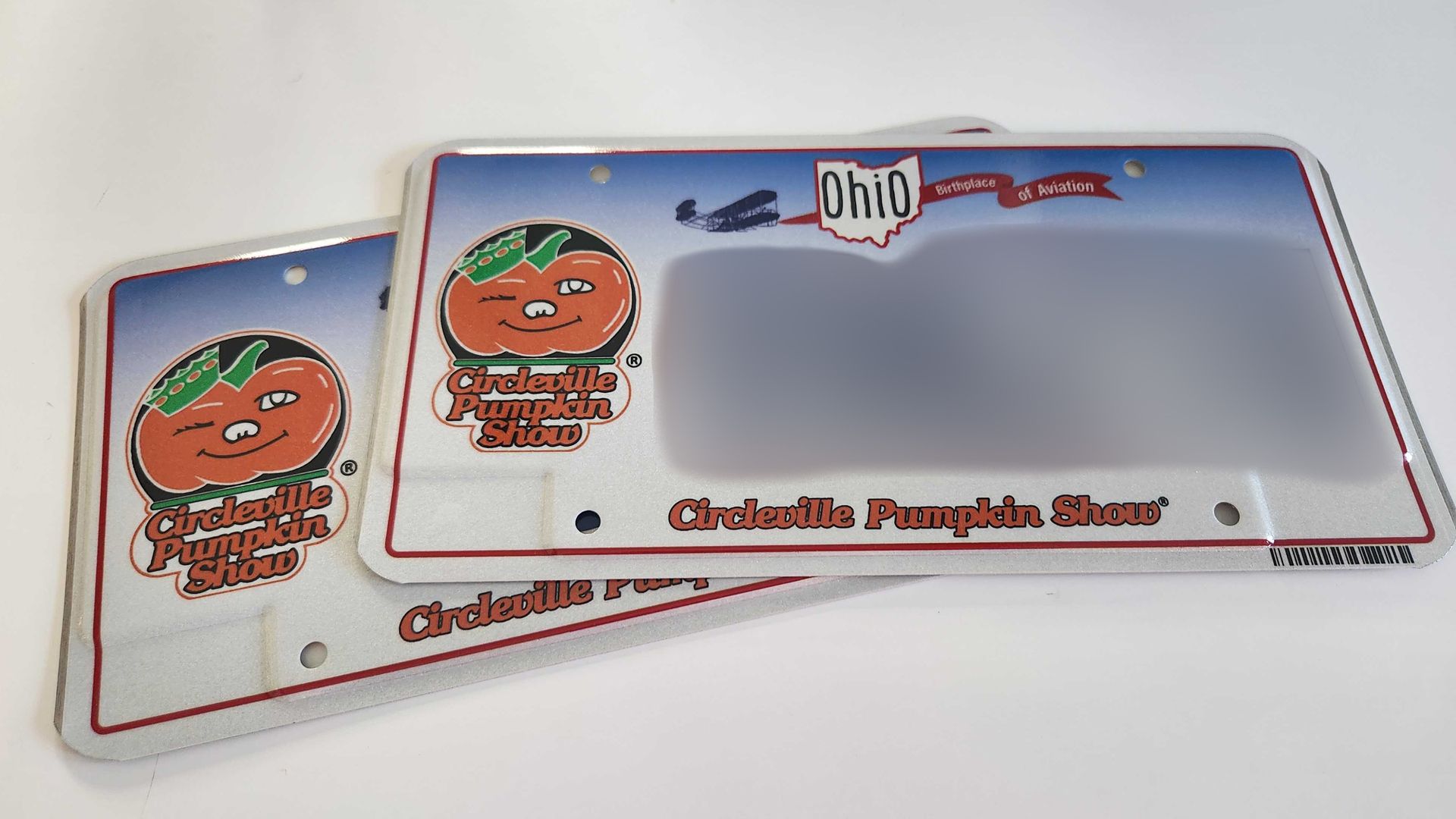 Two license plates with a Circleville Pumpkin Show theme and the plate numbers blurred out. 