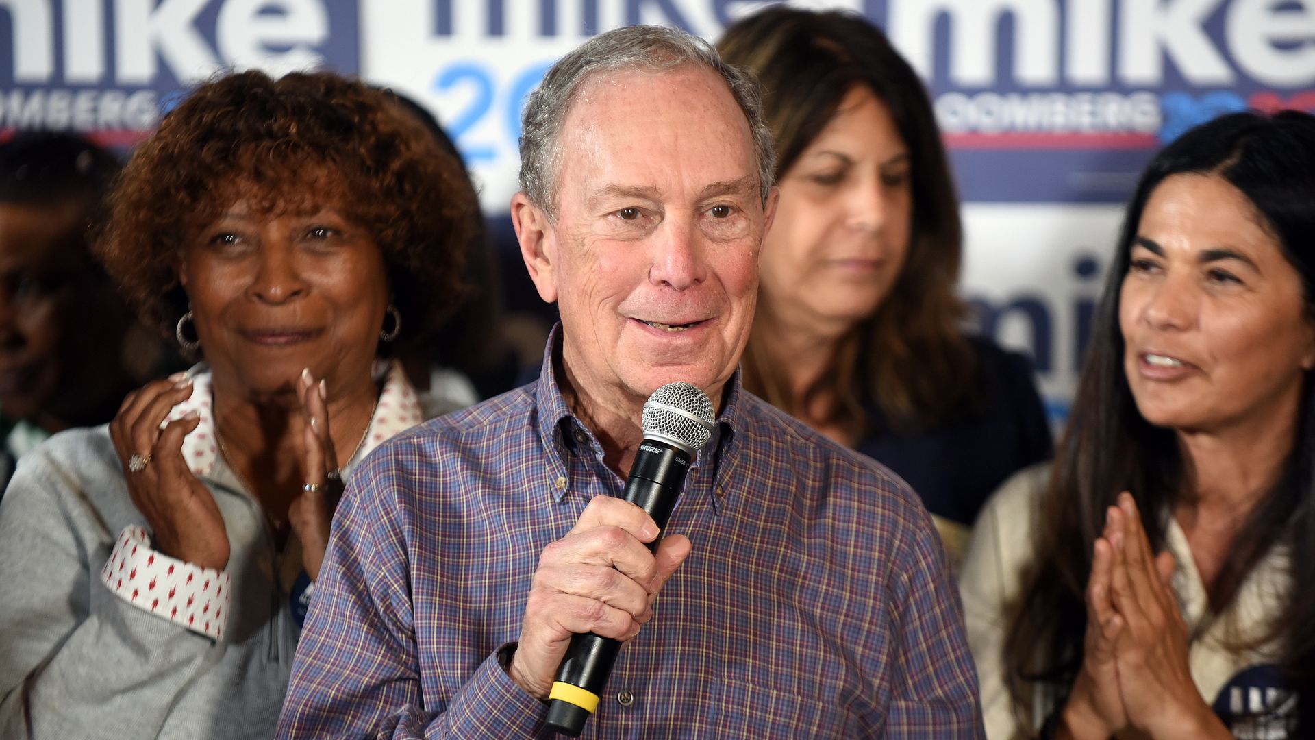 In this image, Bloomberg holds a microphone 