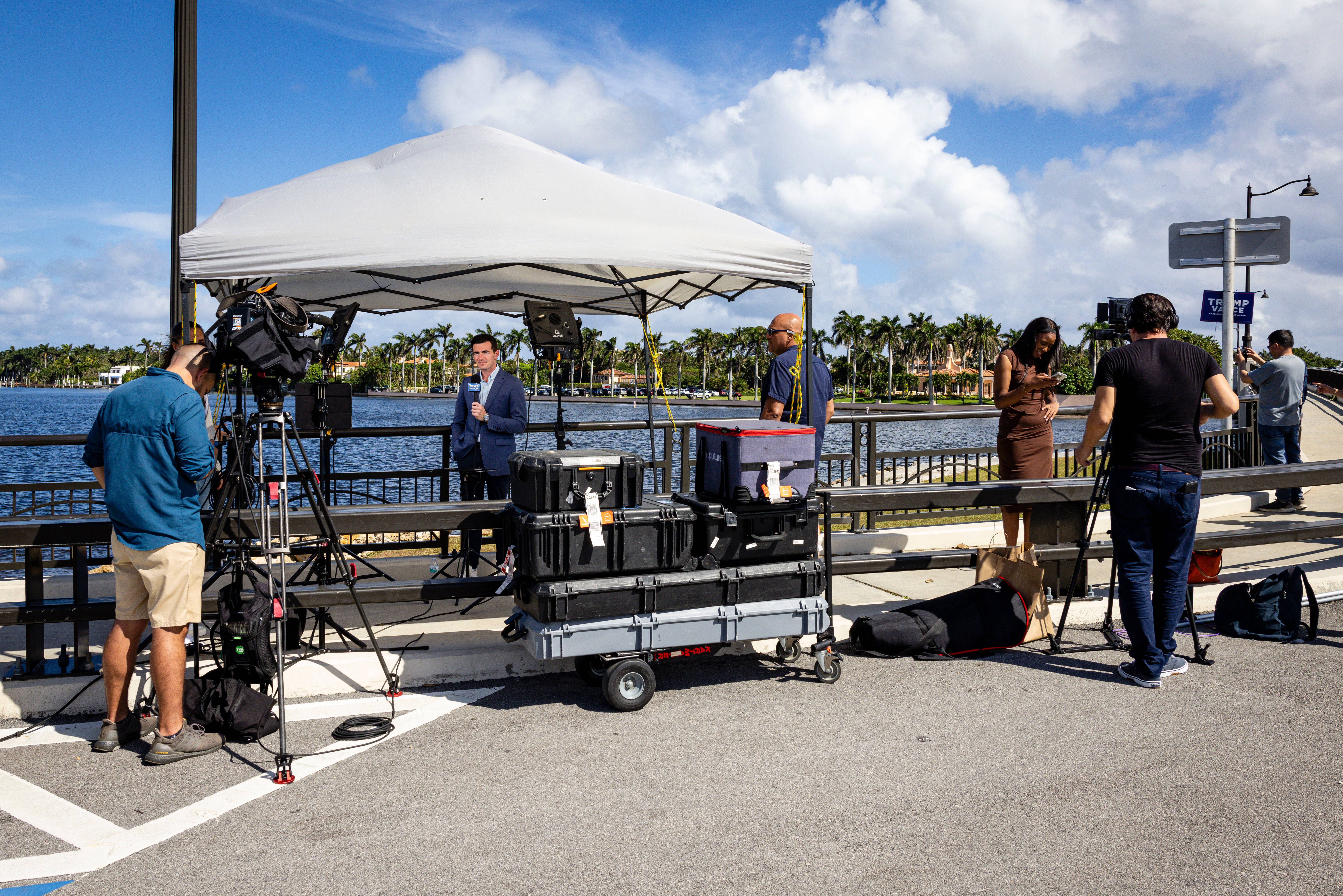 Camera operators and reporters set up by the water