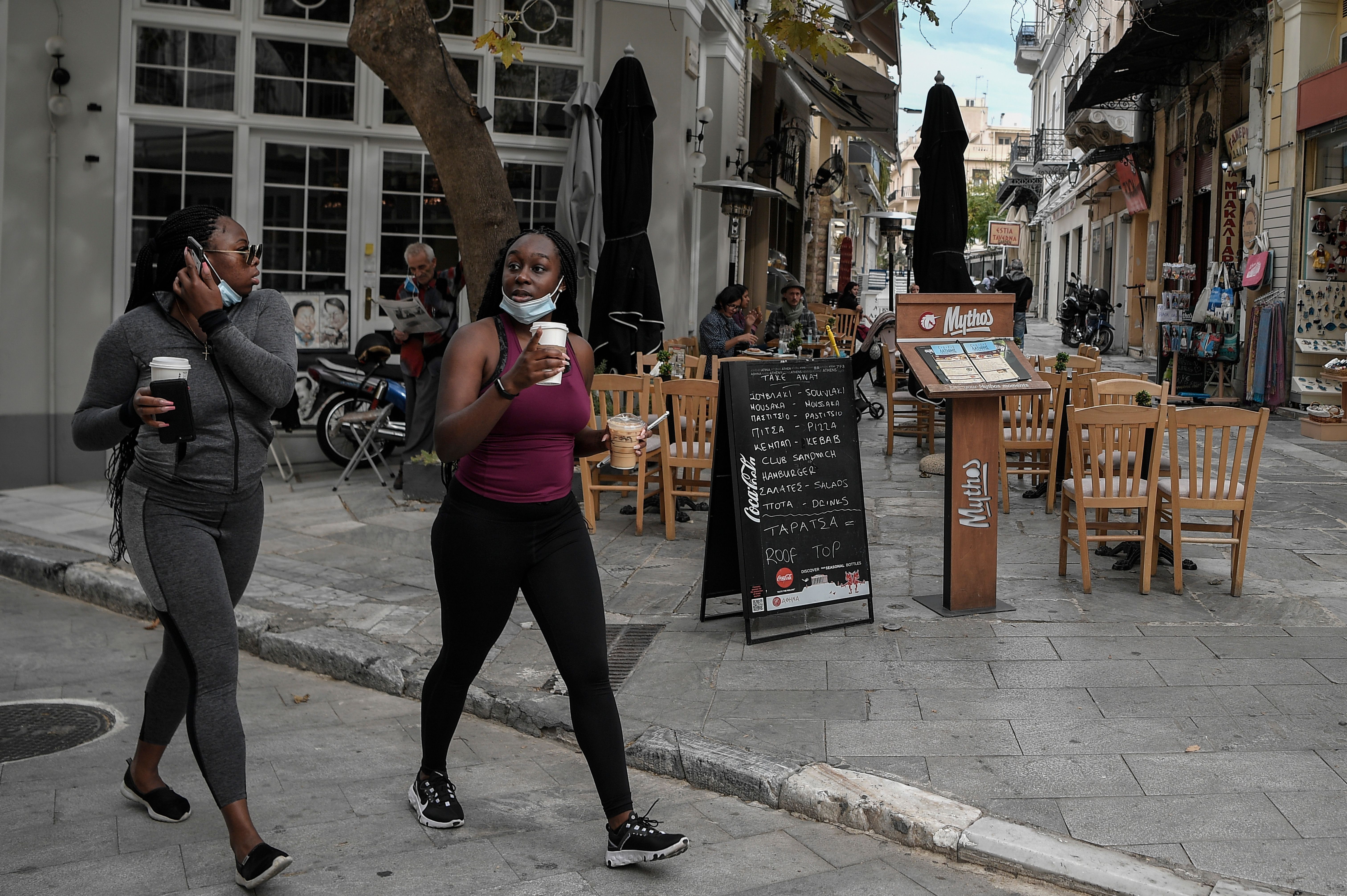 Tourists walk past a cafe in Athens on Nov. 2, as Greece announced new measures such as closing bars, restaurants, cinemas, museums and gyms in red zones, including in the capital. 