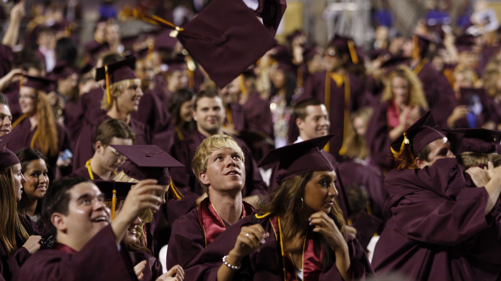 A group of people wearing caps and gowns and throwing their caps in the air.