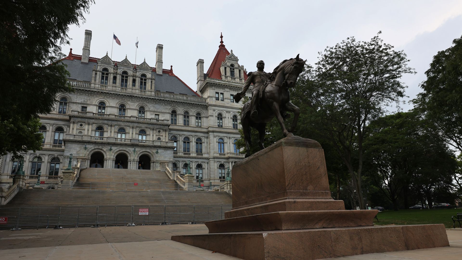 Photo of a statue of a person riding a horse positioned in front of the New York state capitol