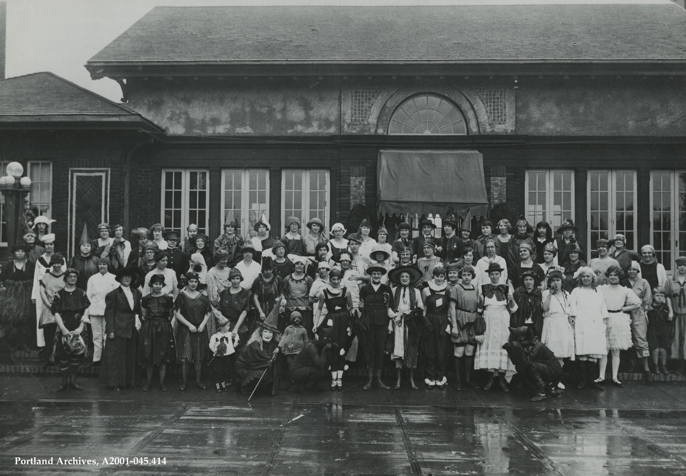 A group of people standing in front of a building all wearing Halloween costumes.