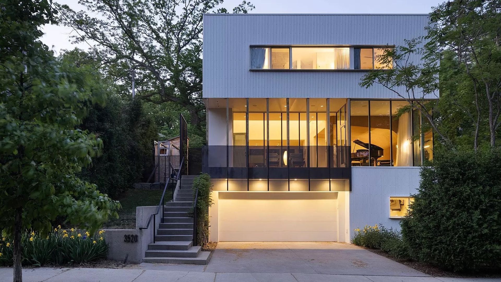 The exterior of a white house with glass walls.