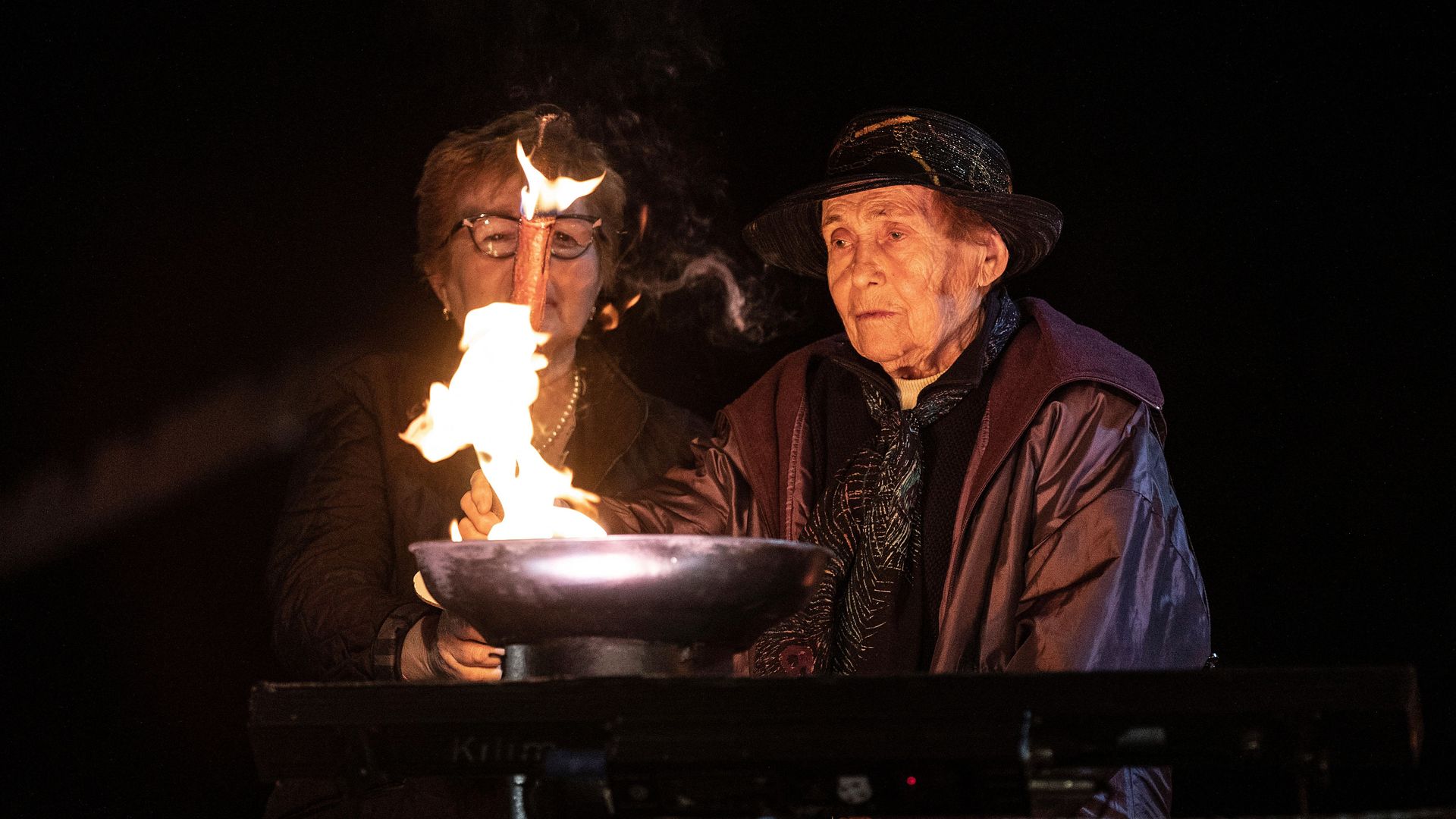 Photo of two people lighting a candle in remembrance of the Holocaust