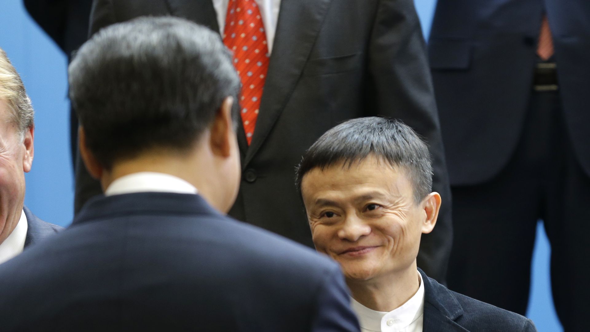 Ma, facing the camera, shakes hands with Xi, back to the camera