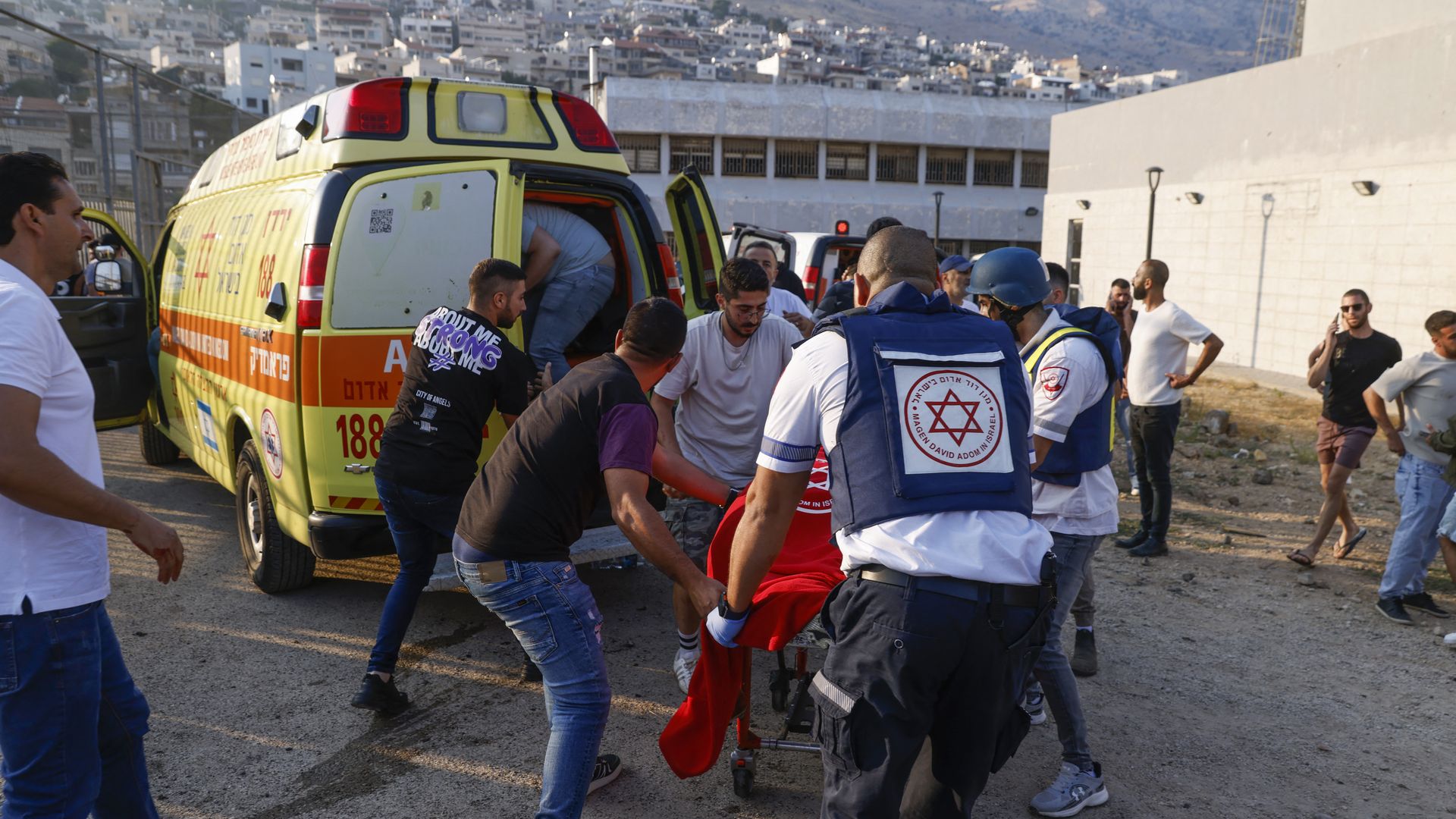 Israeli security forces and medics transport casualties along with local residents, at a site where a reported strike from Lebanon fell in Majdal Shams village in the Golan Heights on July 27, 2024.