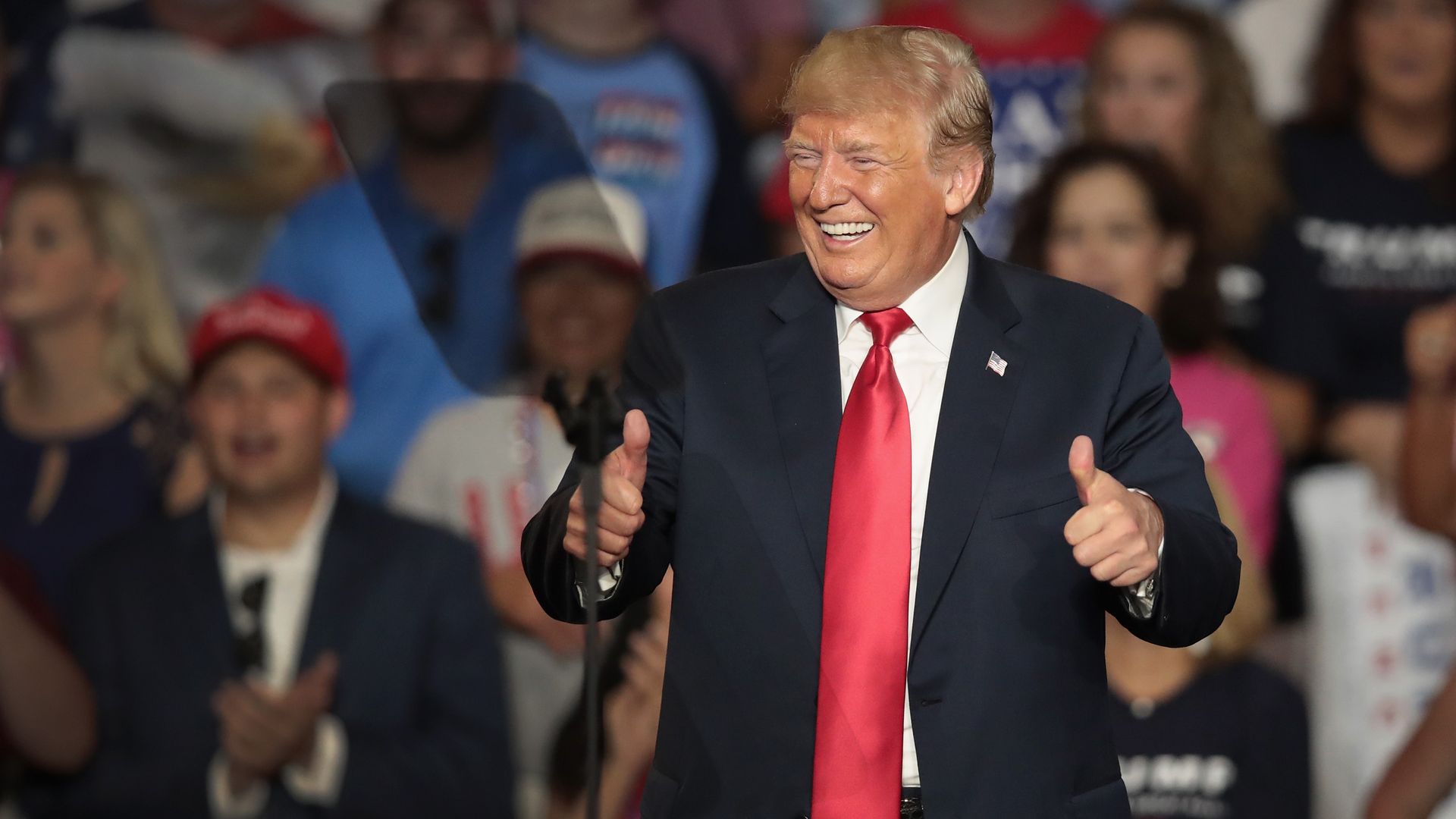 Trump smiles and puts two thumbs up at a rally