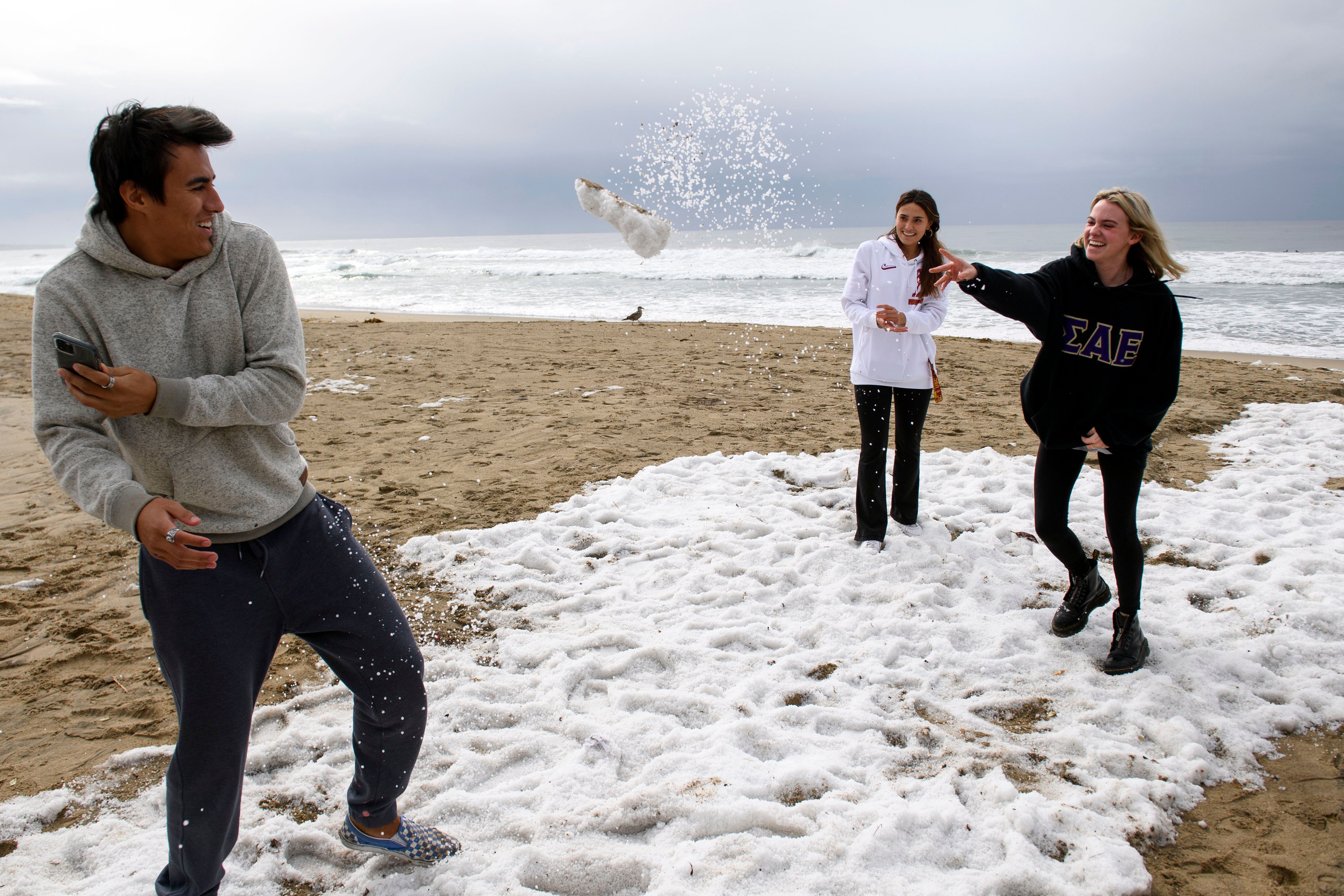 People play with hail on the beach following storms that blanketed the region with rain, snow, and hail, on January 29, 2021 in Manhattan Beach, California